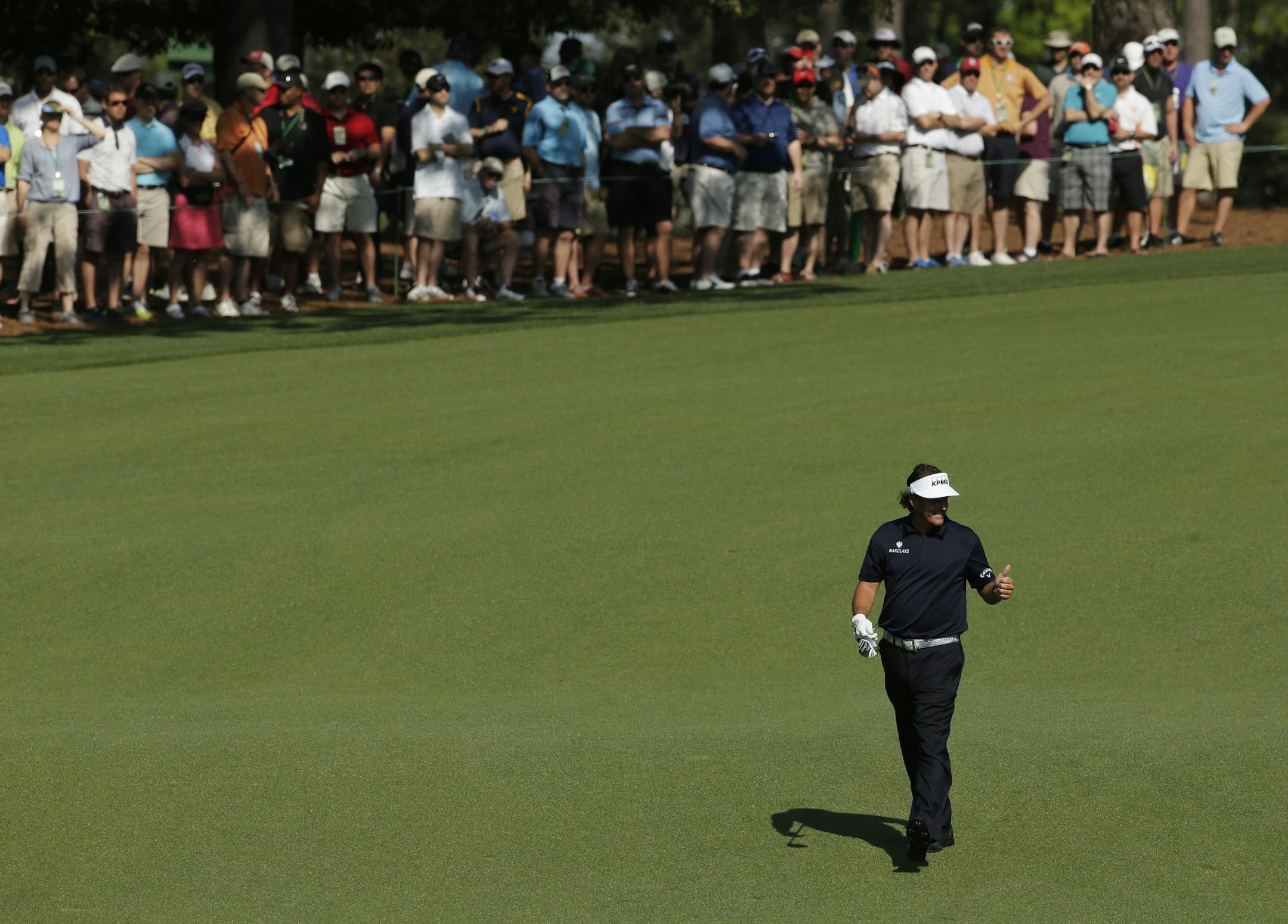 Phil Mickelson gives specters a thumbs up on the ninth fairway during a practice round for the Masters golf tournament Tuesday, April 9, 2013, in Augusta, Ga. (AP Photo/Charlie Riedel)