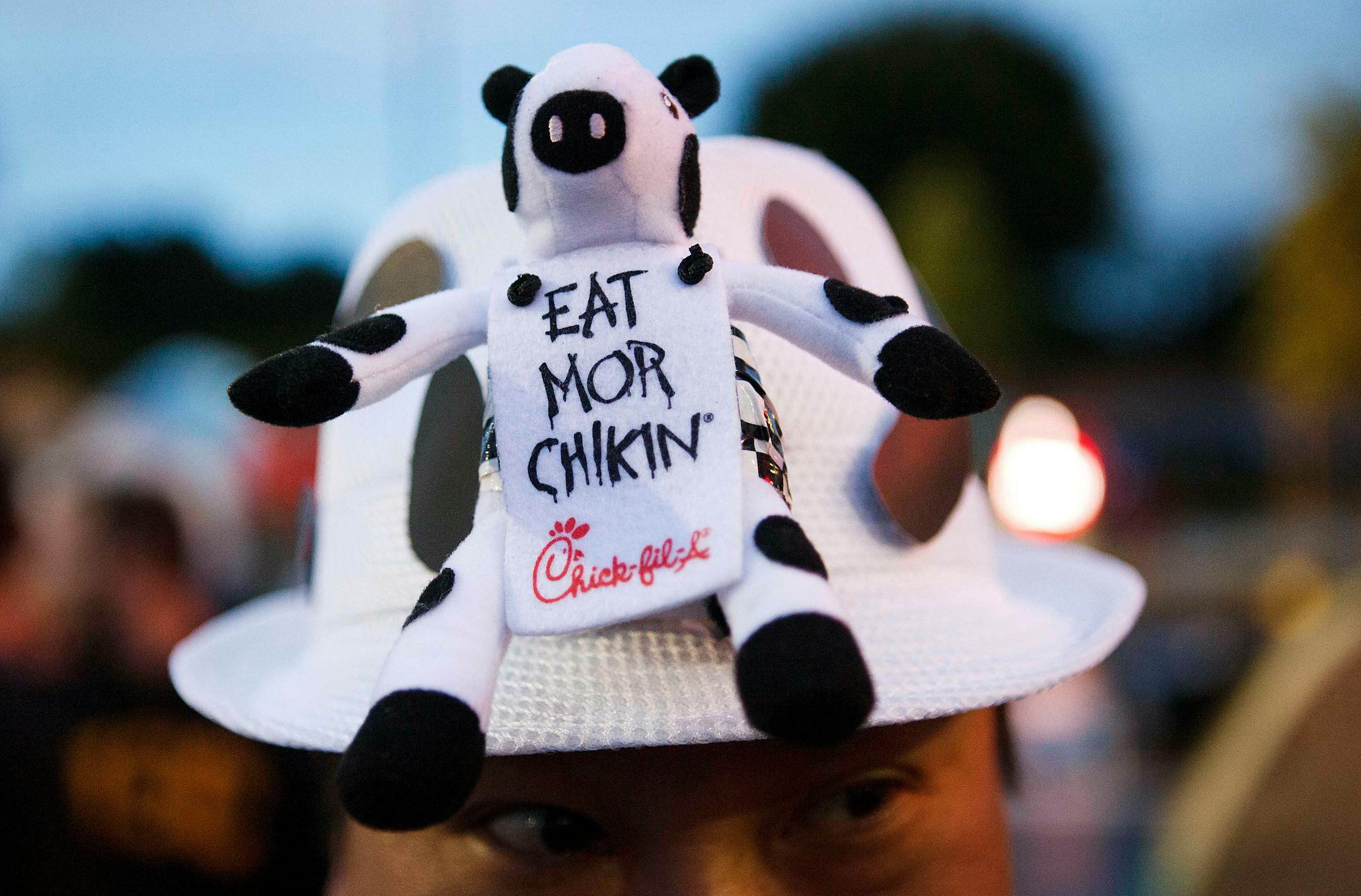Customer Christopher Chen wears a hat with the Chick-fil-A Inc. cow mascot during the grand opening of the company's restaurant in Costa Mesa, California, U.S., on Thursday, April 26, 2012. 100 lucky customers who camped out for over 24 hours received coupons good for a year's worth of free meals. Costa Mesa's first Chick-fil-A restaurant is one of 96 locations the chain plans to open across the country in 2012, creating nearly 7,000 new jobs according to the company. Photographer: Patrick Fallo