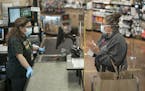 Linden Hills Co-op cashier Sareena Tippett wore a mask as she helped customer Cindy Lambing on May 21. Minneapolis requires face coverings inside busi