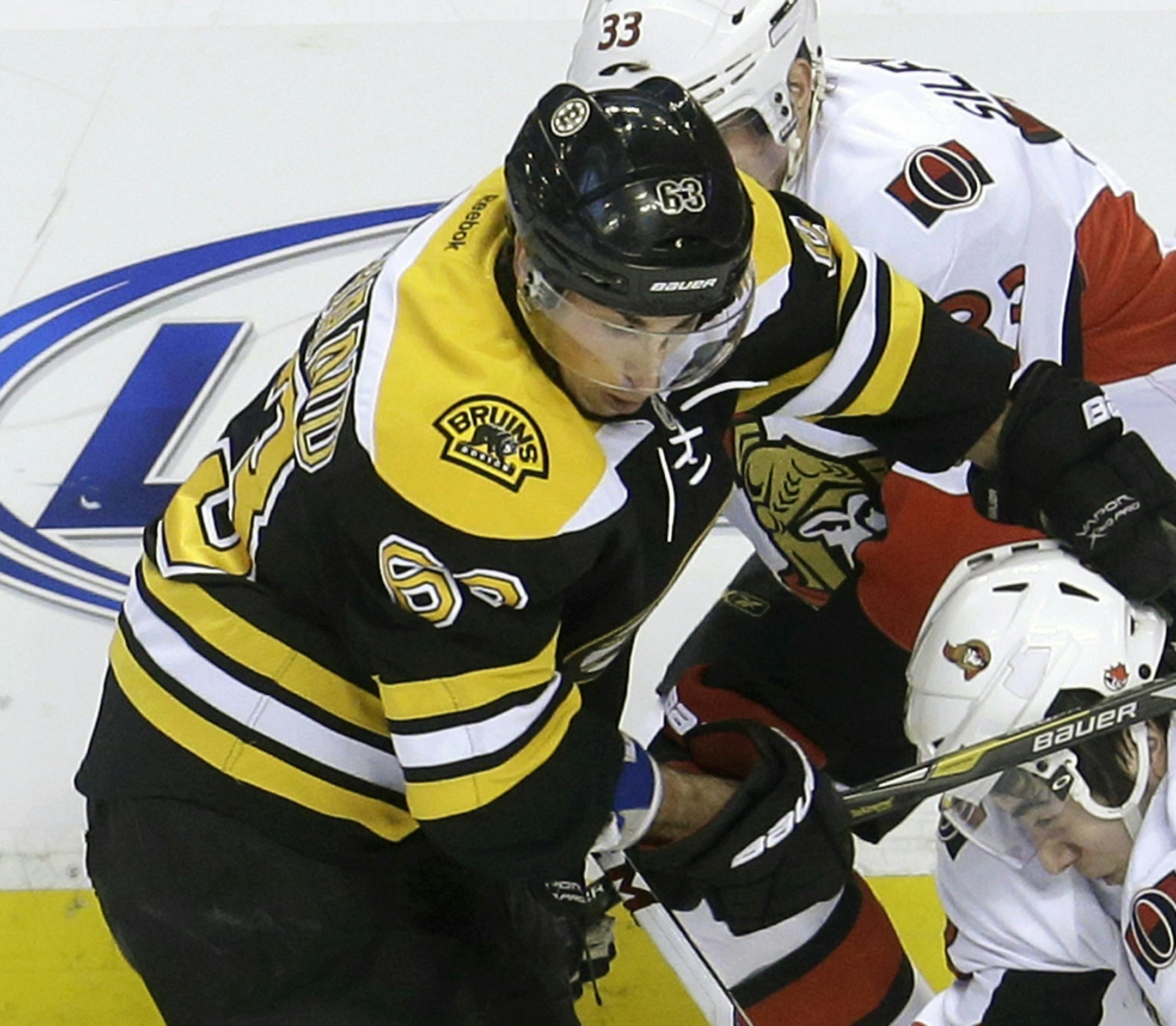 Boston Bruins left wing Brad Marchand (63), left, collides with Ottawa Senators center Mika Zibanejad (93), right, of Sweden, in the first period of an NHL hockey game in Boston, Sunday, April 28, 2013. Senators left wing Jakob Silfverberg, background, skates behind. (AP Photo/Steven Senne)