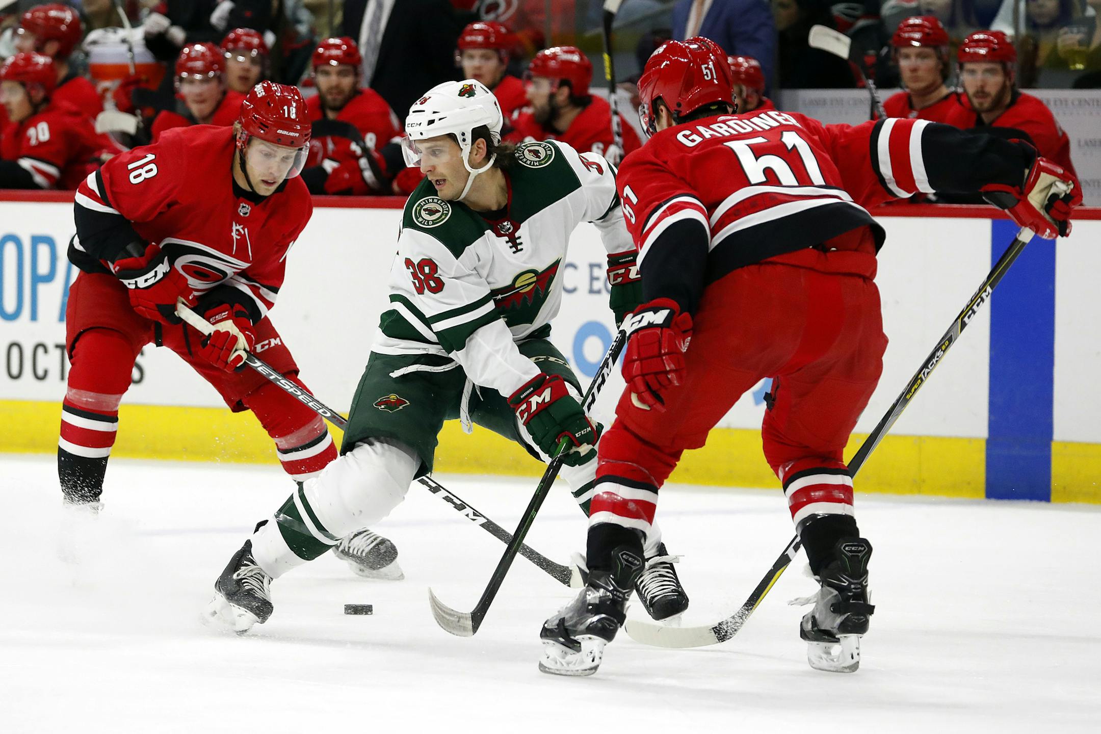 Carolina Hurricanes' Jake Gardiner (51) tips the puck away from Minnesota Wild's Ryan Hartman (38) leaving it for teammate Ryan Dzingel (18) during the first period of an NHL hockey game in Raleigh, N.C., Saturday, Dec. 7, 2019. (AP Photo/Karl B DeBlaker)