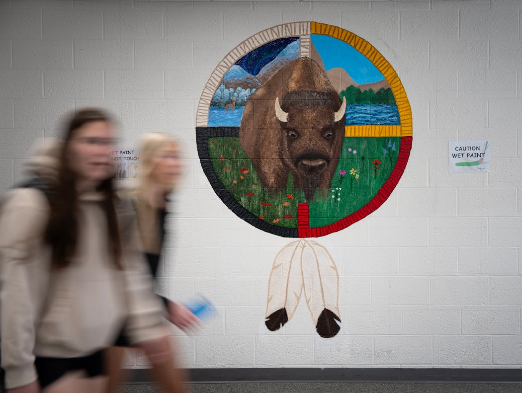 Students pass by a mural being painted by senior Lexi Sanburg in a hallway of Centennial High School on Thursday. 