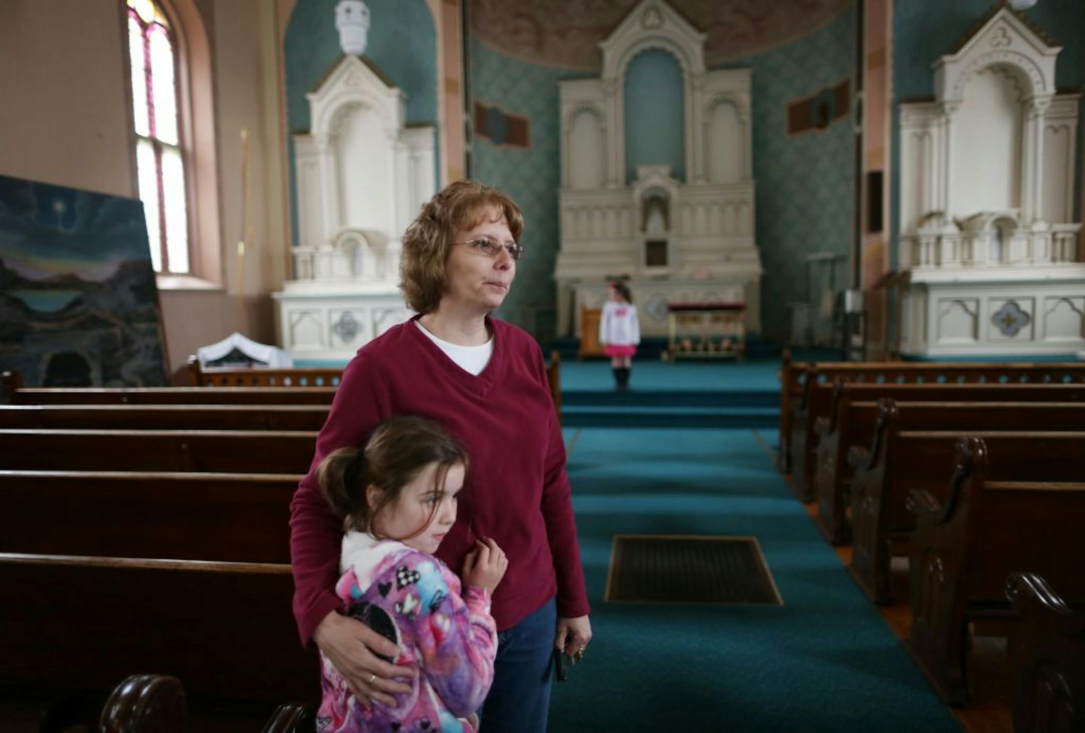 Diane Weckman held her granddaughter, Avery, 5, as she remembered the past in the vacant St. Benedict's church in New Prague on Friday.