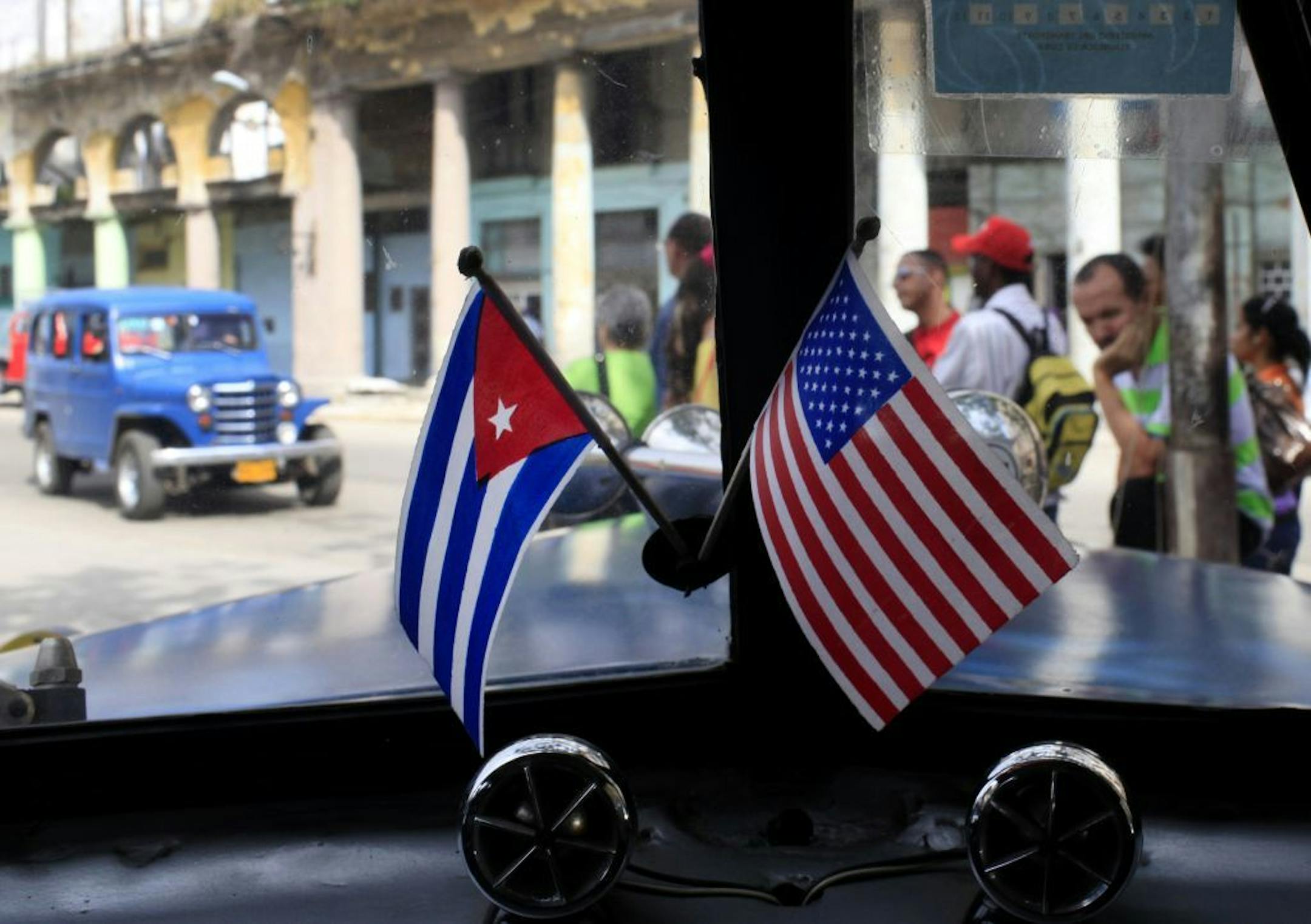 FILE - In this March 22, 2013 file photo, miniature flags representing Cuba and the U.S. are displayed on the dash of a classic American car in Havana, Cuba. After decades of U.S. efforts to foment democracy by backing Cuba's dissidents and their demands for swift political change, President Barack Obama's trip in March 2016 will showcase a 180-degree turn in U.S. policy toward the island. The U.S. is wagering that re-forging links between the U.S. and Cuba will do more to change Cuba�s single-p