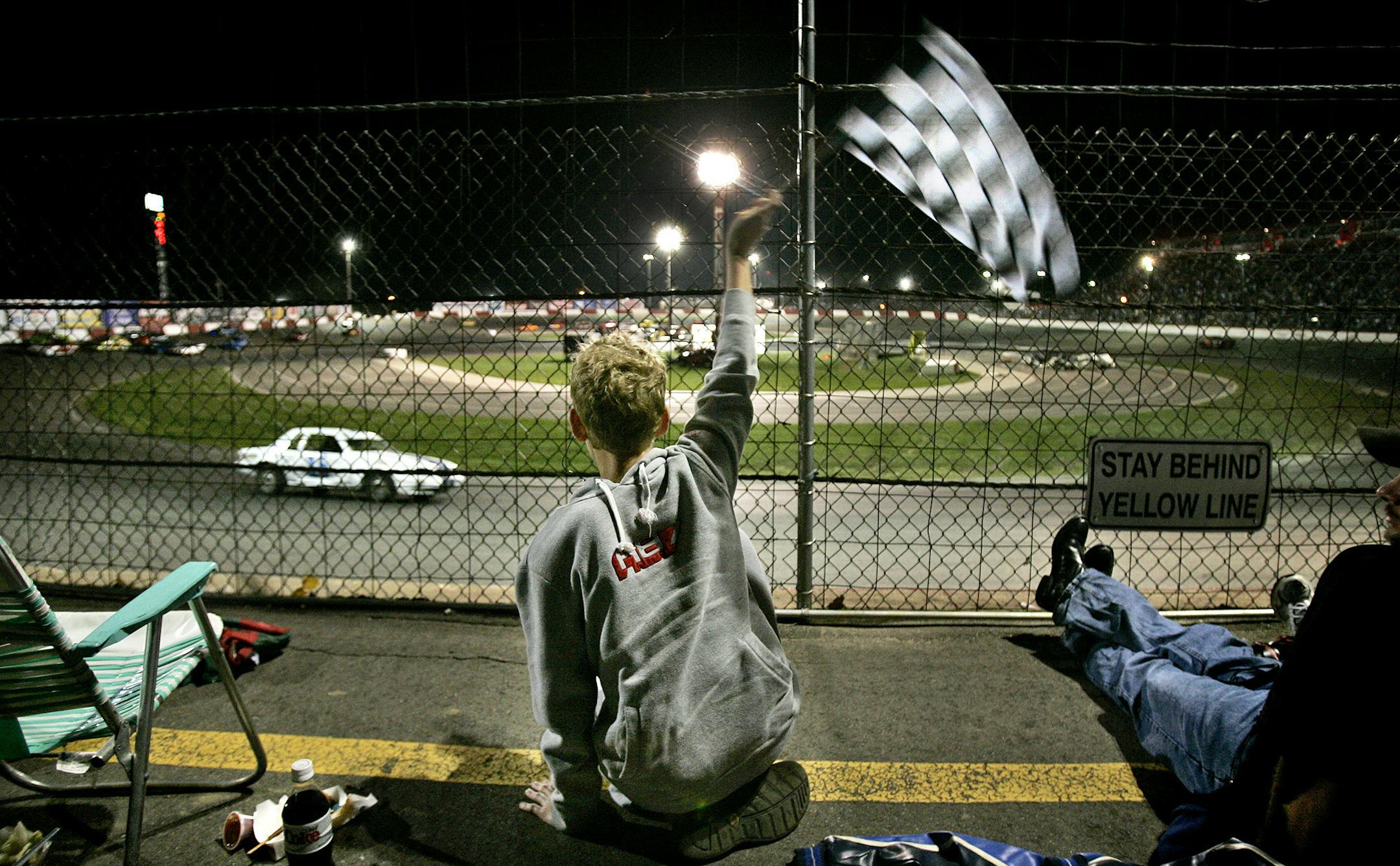 Jared Moderie, 13, of Eagan waves a checkered flag he purchased during a cruiser race during the Eve of Destruction racing event at the Elko Speedway, Elko, Minn., August 27, 2005.