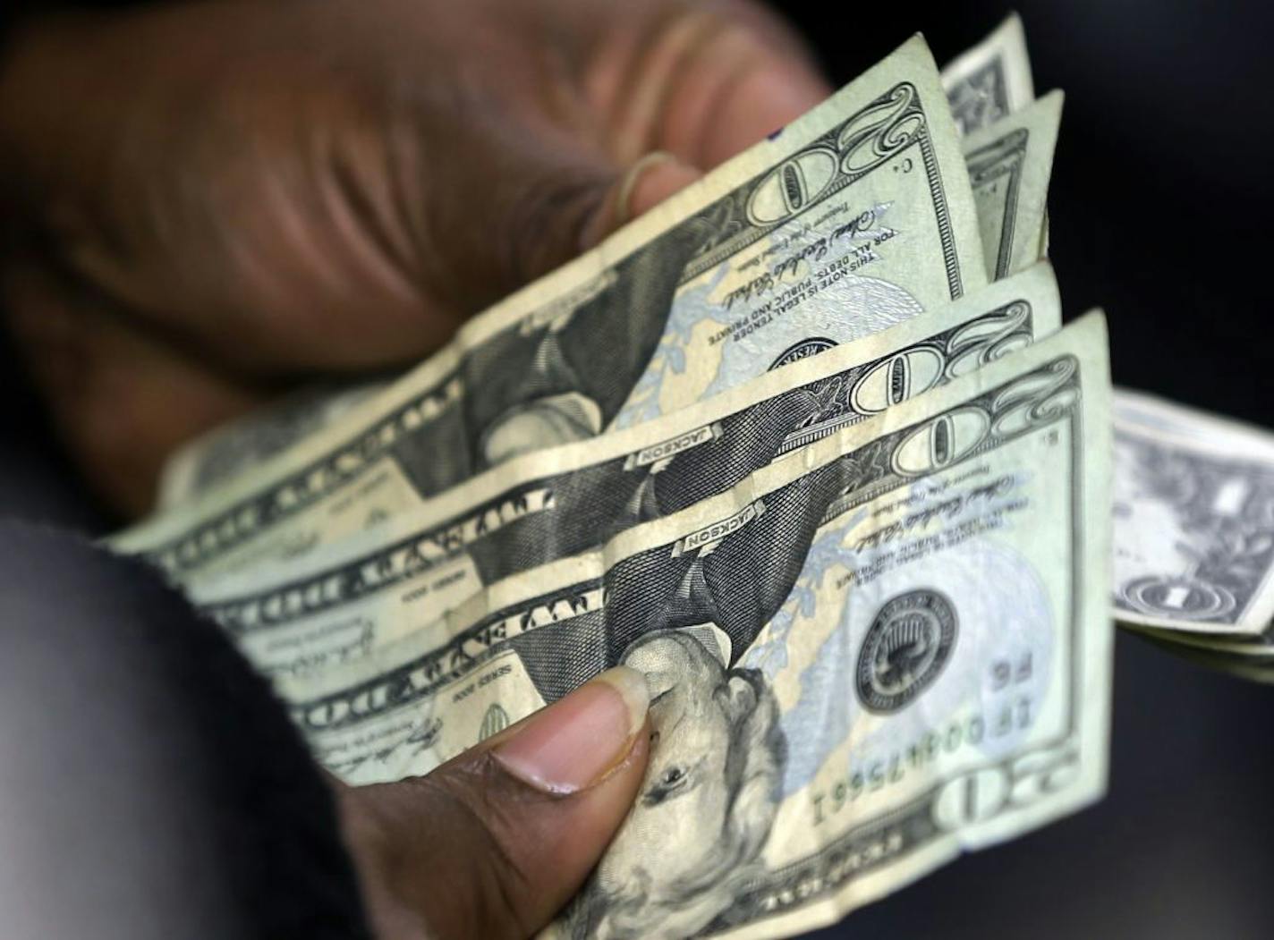 In this Monday, Feb. 25, 2013 photo, a customer counts her change after a purchase at Lodge's store in Albany N.Y. U.S. consumers earned more and spent more in February, helped by a stronger job market that offset some of the drag from higher taxes, according to the Commerce Department, Friday, March 29, 2013.