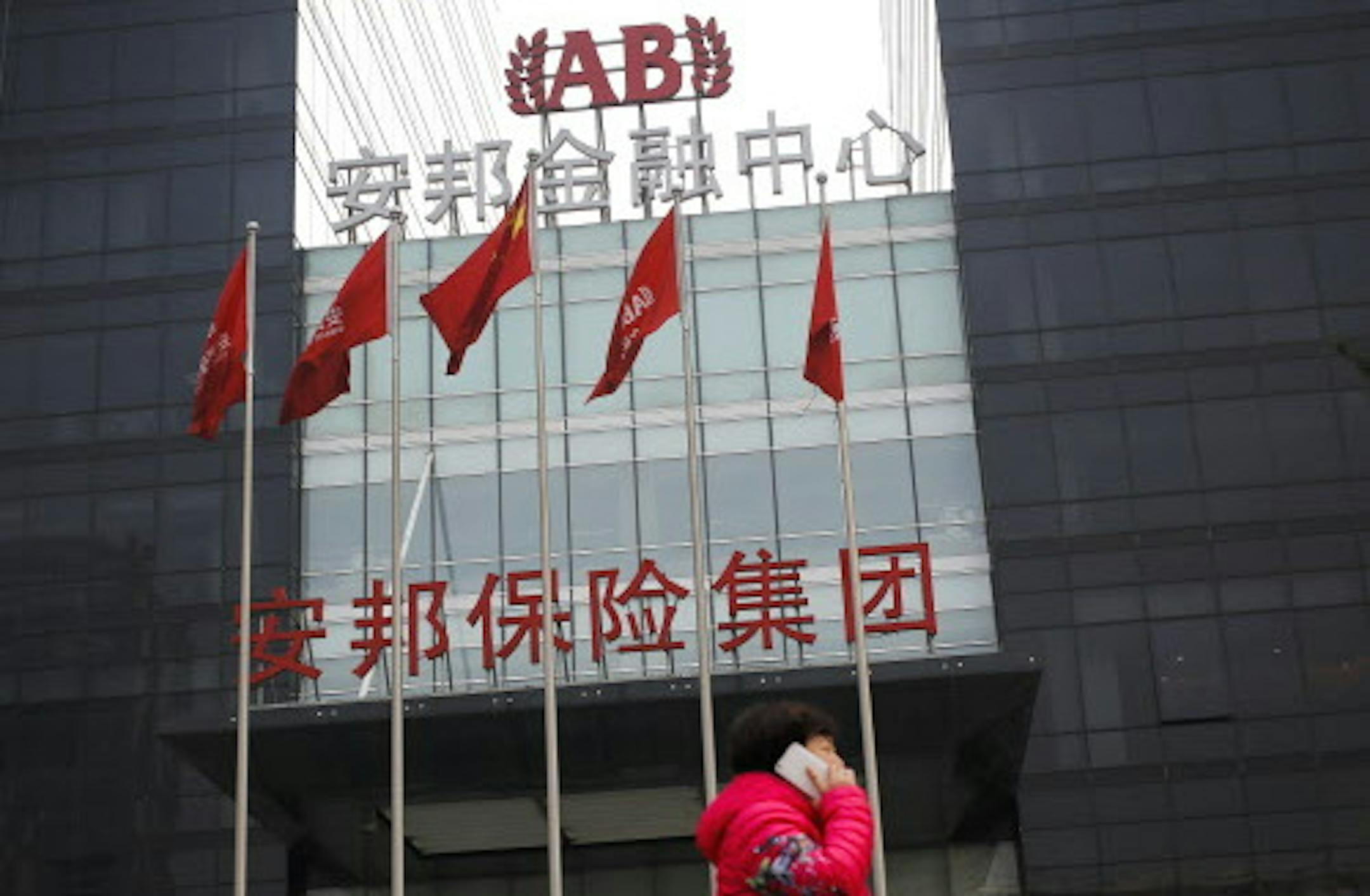A woman walks past the Anbang Insurance Group's building in Beijing, Wednesday, March 16, 2016. Young, privately owned and ambitious, Anbang Insurance Group stands out in China's staid, state-dominated insurance industry. Founded just 12 years ago, Anbang made a splash in the United States in 2014 with its $2 billion purchase of New York City's Waldorf Astoria Hotel. On Monday, March 14, it went after even bigger game, launching a surprise $14 billion bid with partners for the Starwood hotel cha