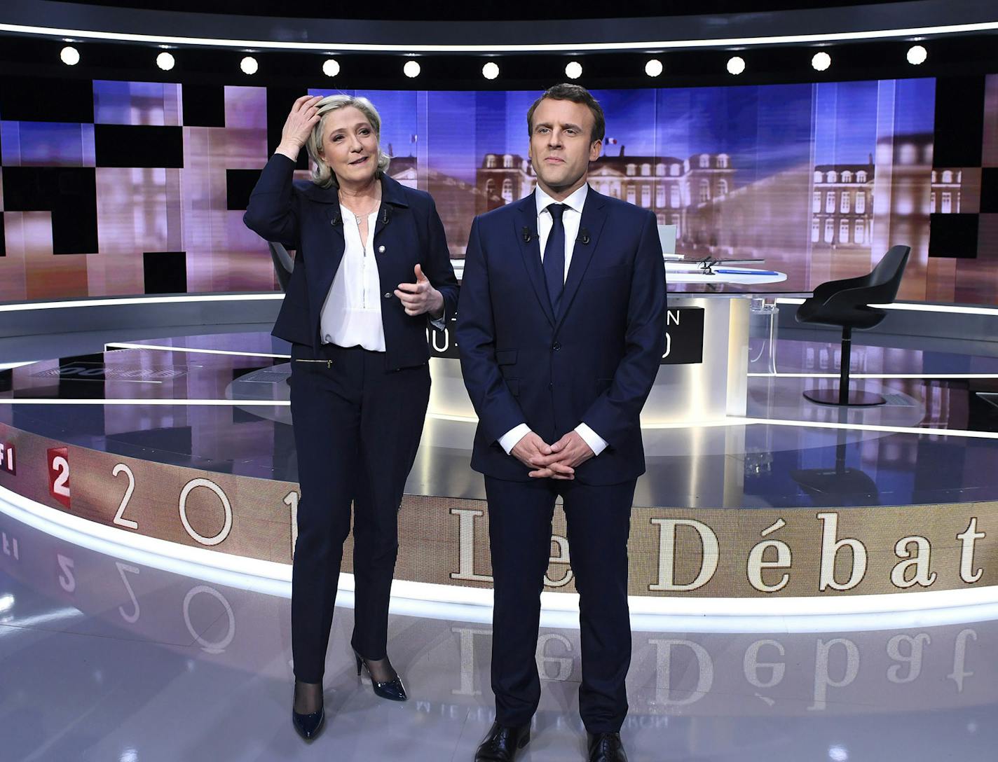 French presidential election candidate for the far-right Front National party, Marine Le Pen, 2nd left, and French presidential election candidate for the En Marche ! movement, Emmanuel Macron, right, pose prior to the start of a live broadcast face-to-face televised debate in La Plaine-Saint-Denis, north of Paris, France, Wednesday, May 3, 2017 as part of the second round election campaign. Pro-European progressive Emmanuel Macron and far-right Marine Le Pen are facing off in their only direct