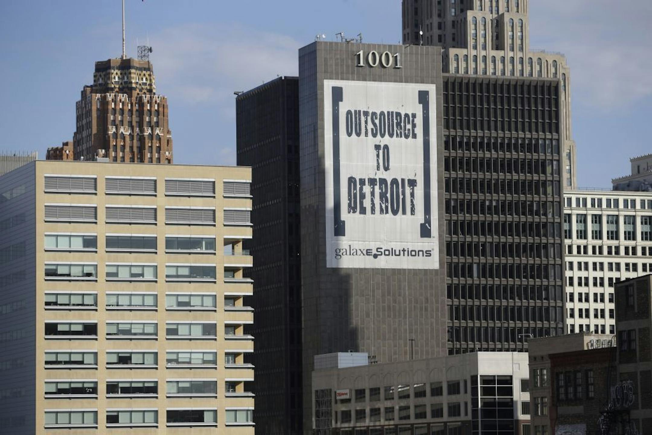 In this July 12, 2013, photo an Outsource to Detroit banner from Galaxe.Solutions is seen on a Detroit building. After several weeks of slow-moving talks, only one deal has been reached between the state-appointed emergency manger hired to fix Detroit's finances and the more than 50 creditors, two public pension funds and unions jockeying for a piece of the billions of dollars the city owes them. The pace is frustrating for some, who are balking at the 10 cents on a dollar offered by bankruptcy