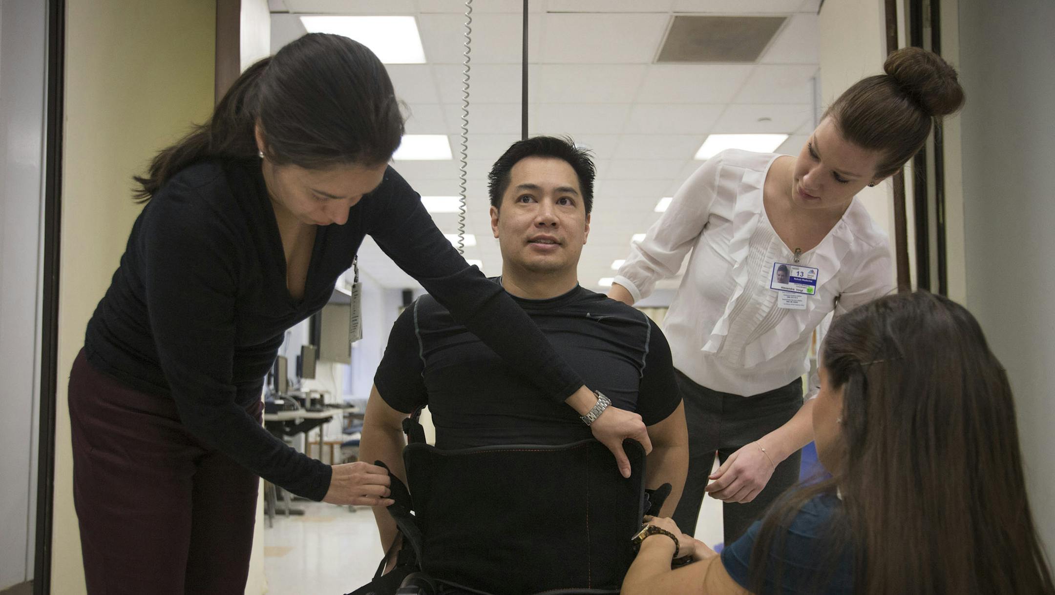 Robert Woo, 45, is helped into an Ekso Bionics "exoskeleton," at Mount Sinai Medical Center in New York, U.S., on Thursday, March 14, 2013. Wearable machines that enhance human muscle power are poised to leave the realm of science fiction and help factory workers hoist heavier tools, lighten soldiers‚àö‚â† loads and enable spinal patients to walk. Photographer: Scott Eells/Bloomberg *** Local Caption *** Robert Woo