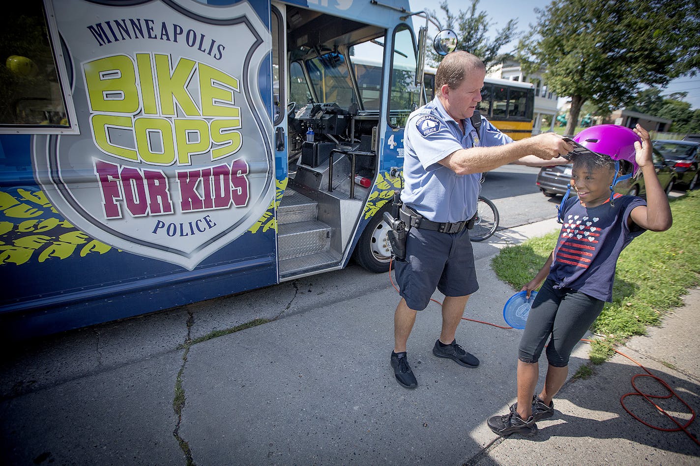 Minneapolis Police Officer Michael Kirchen was more than happy to pass along a free helmet to Jahnyra Lane, 10, cq, while she visited a community outreach BBQ, Thursday, August 24, 2017 in Minneapolis, MN. Bike Cops 4 Kids, a long-running community engagement program that helps at-risk kids, giving away bikes and equipment, hosting events and even showing up at murder scenes to show a different face of the department. ] ELIZABETH FLORES &#x2022; liz.flores@startribune.com