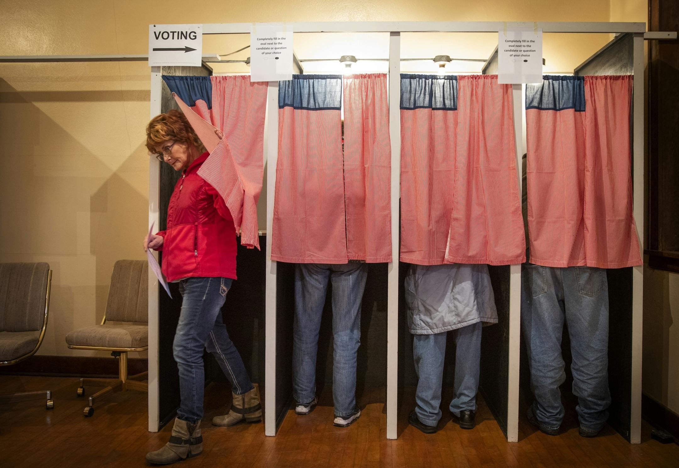 Christine Giroux exits the voting booth at Transit Town Hall. The curtains, an ode the American flag, were sewn by a past election official.