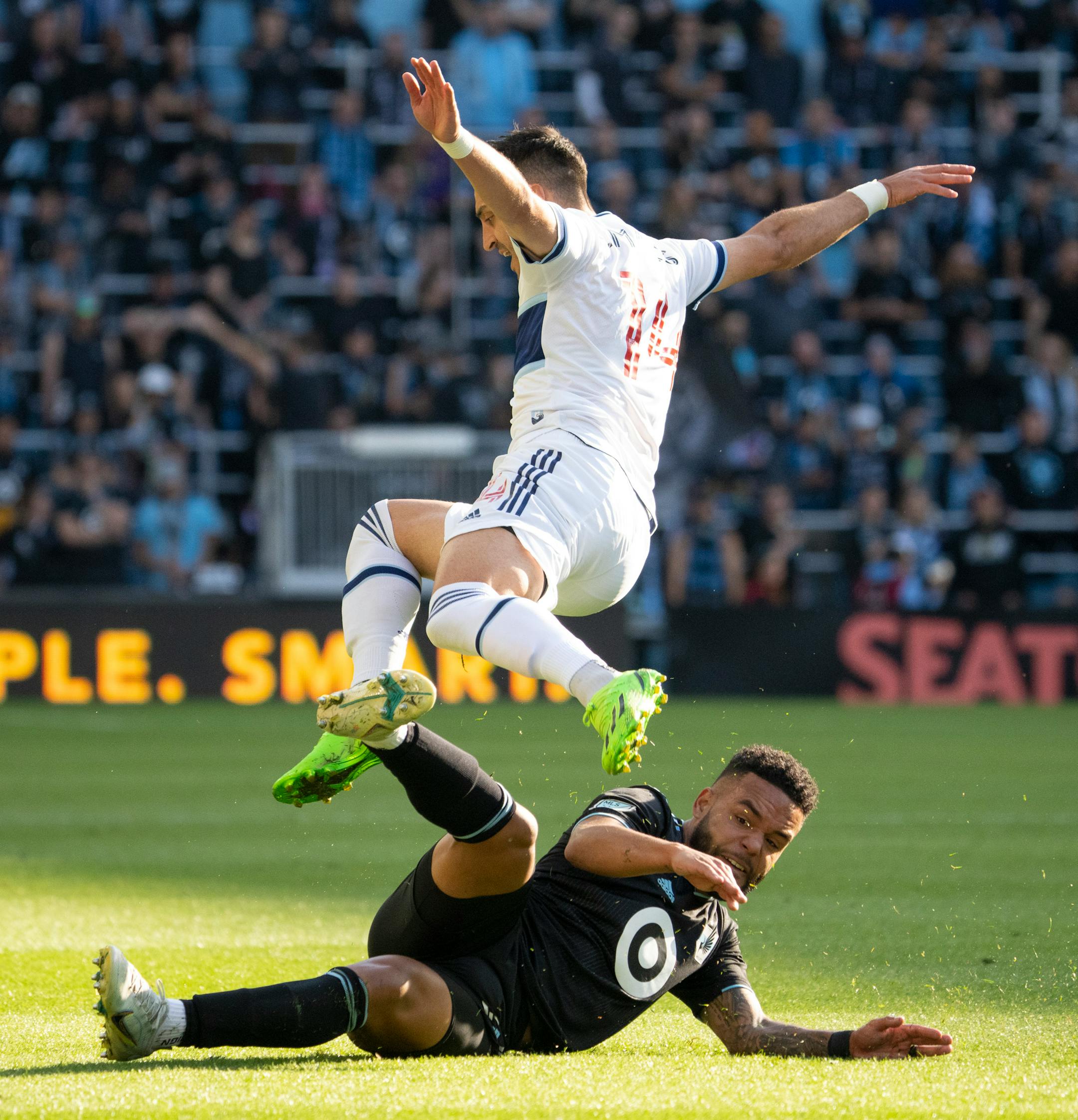 Vancouver Whitecaps defender Lu's Martins (14) leapt over Minnesota United defender D.J. Taylor (27) after Taylor took the ball from him in the first half.