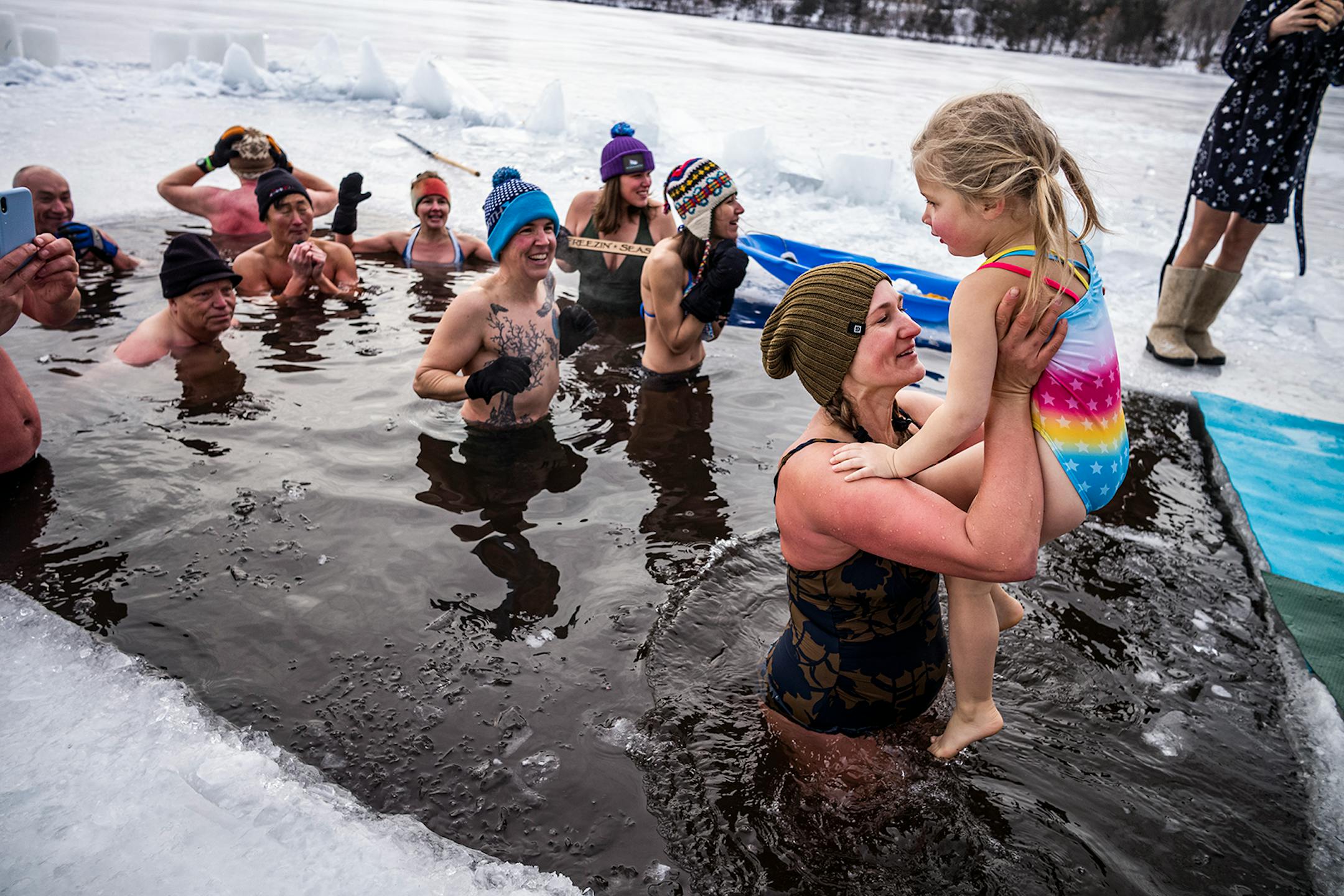 Svetlana Vold helps her youngest daughter, Yeva, 4, take a quick dip in the ice chopped into Cedar Lake in Minneapolis. Throughout the winter, biohackers maintain a a hole in the ice chopped into Cedar Lake in Minneapolis in the belief that regular cold water immersions make them healthier