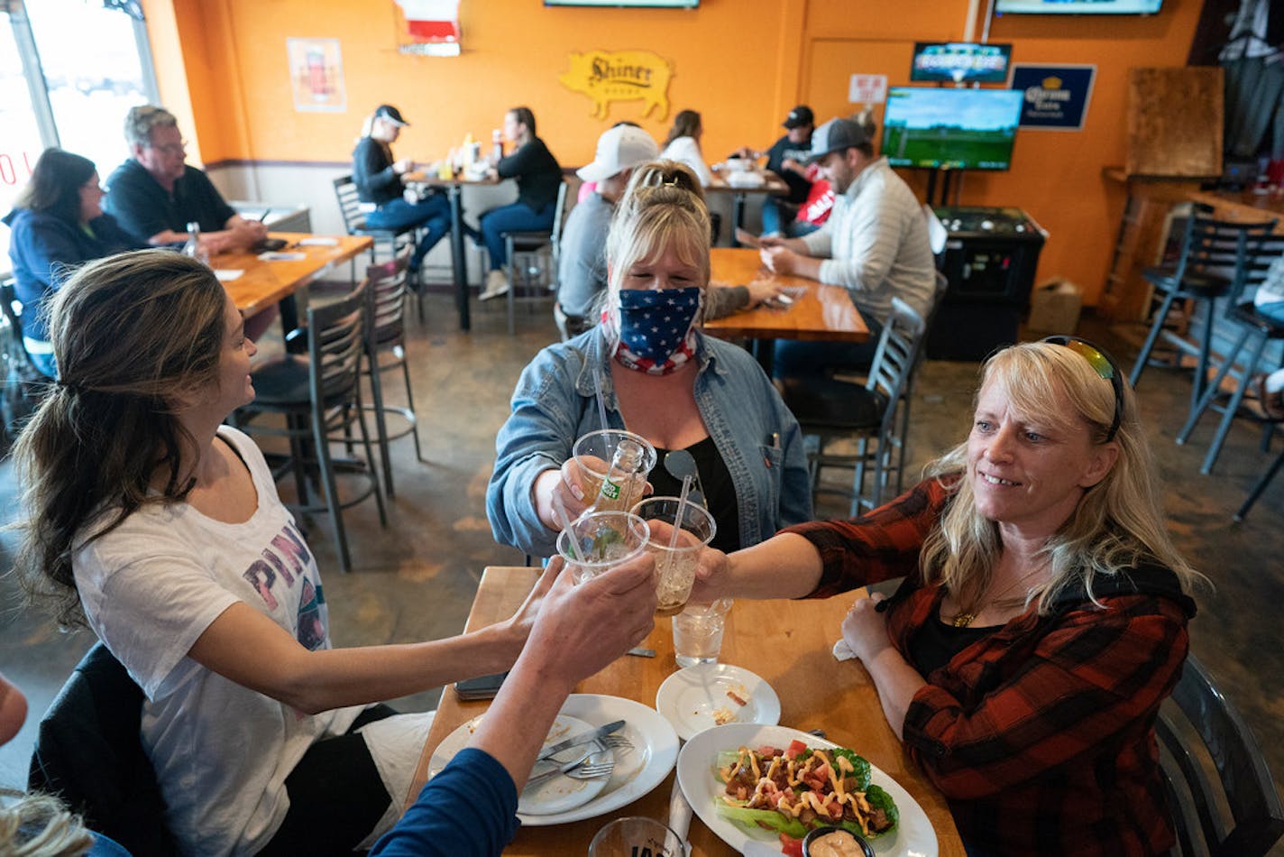 Friends, from left, Tracey, who did not give her last name, Cindy Coleman and Lori Stayberg met for food and drinks at Jonesy's Local Bar on the first day of the bar reopening in Hudson, Wis., on May 14, 2020.