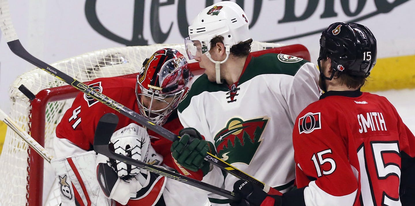 Minnesota Wild's Charlie Coyle, middle, and Ottawa Senators goaltender Craig Anderson (41) watch a loose puck as Senators' Zak Smith (15) defends during the second period of an NHL hockey game Tuesday, March 15, 2016, in Ottawa, Ontario. (Fred Chartrand/The Canadian Press via AP)