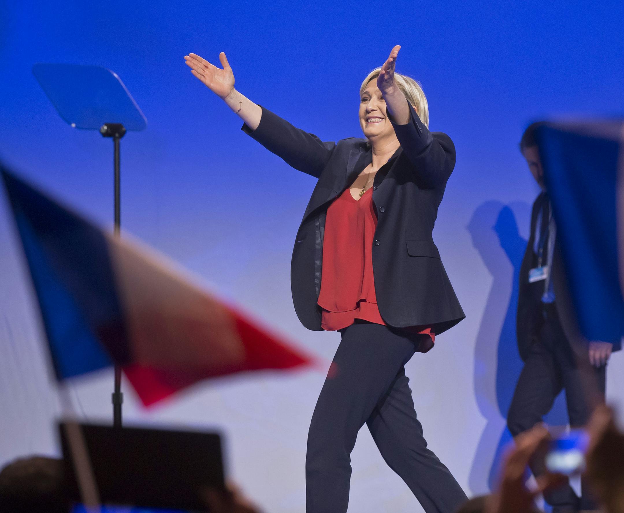 Far-right leader and candidate for the 2017 French presidential election Marine Le Pen acknowledges applauses as she arrives on stage for a meeting in Marseille, southern France, Wednesday, April 19, 2017. Le Pen and centrist Emmanuel Macron are among four leading candidates seen as most likely to progress from Sunday's first round and to reach the May 7 runoff between the top two. (AP Photo/Michel Euler)