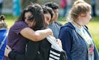 Santa Fe High School freshman Caitlyn Girouard, center, hugs her friend outside the Alamo Gym where students and parents wait to reunite following a s