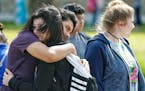 Santa Fe High School freshman Caitlyn Girouard, center, hugs her friend outside the Alamo Gym where students and parents wait to reunite following a s