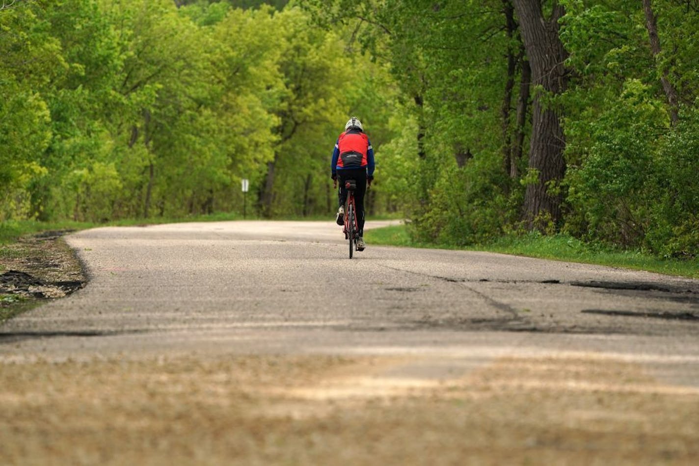 A cyclist road illegally down the main road leading into Fort Snelling State Park past a section that has been temporarily repaired after it was damaged by flooding.