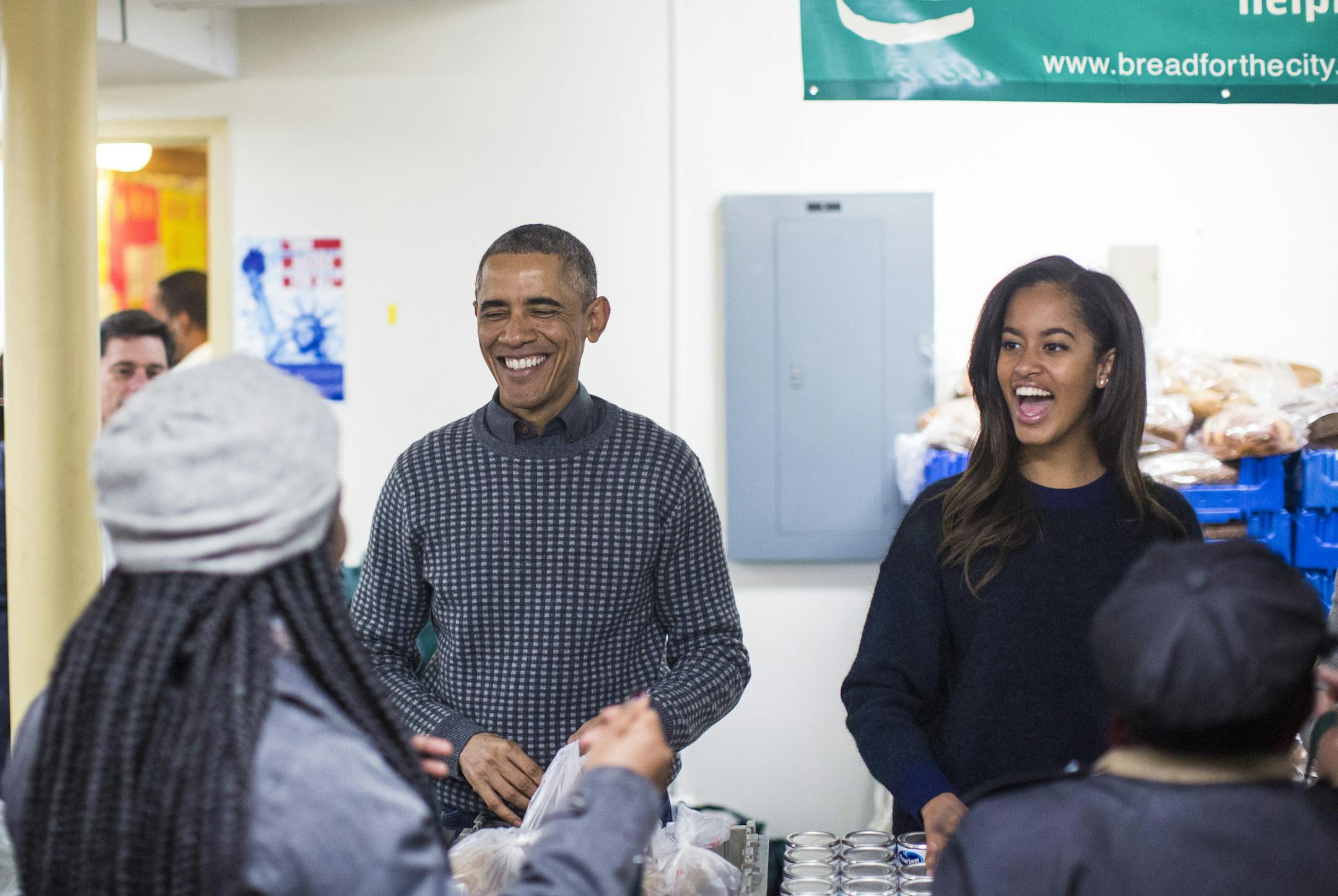 President Barack Obama and his daughter, Malia, hand out food during a Thanksgiving service event at Bread for the City food bank in Washington, Nov. 26, 2014. (Jabin Botsford/The New York Times)