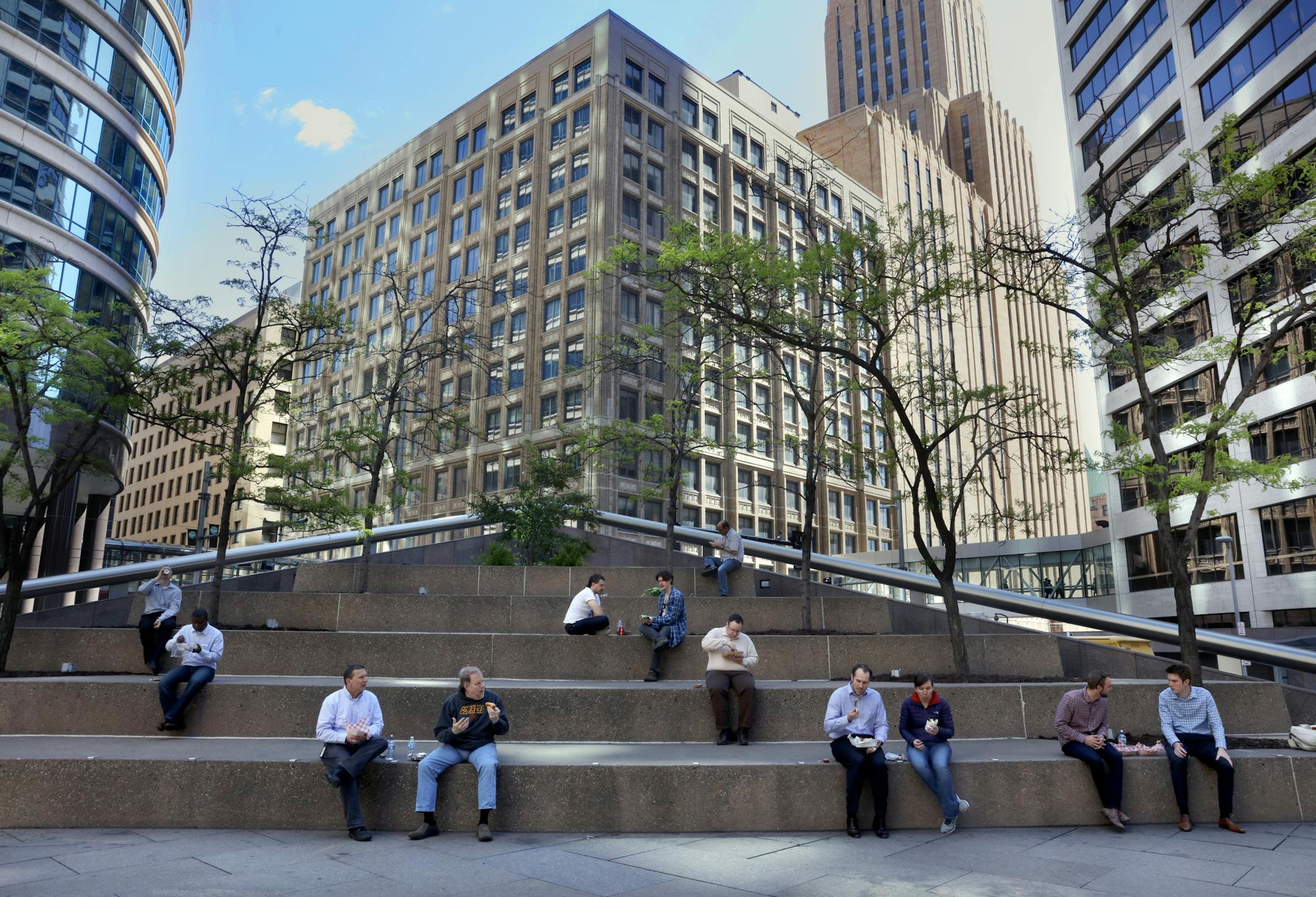Folks settle in for lunch break on the large steps outside the Canadian Pacific building in downtown Minneapolis