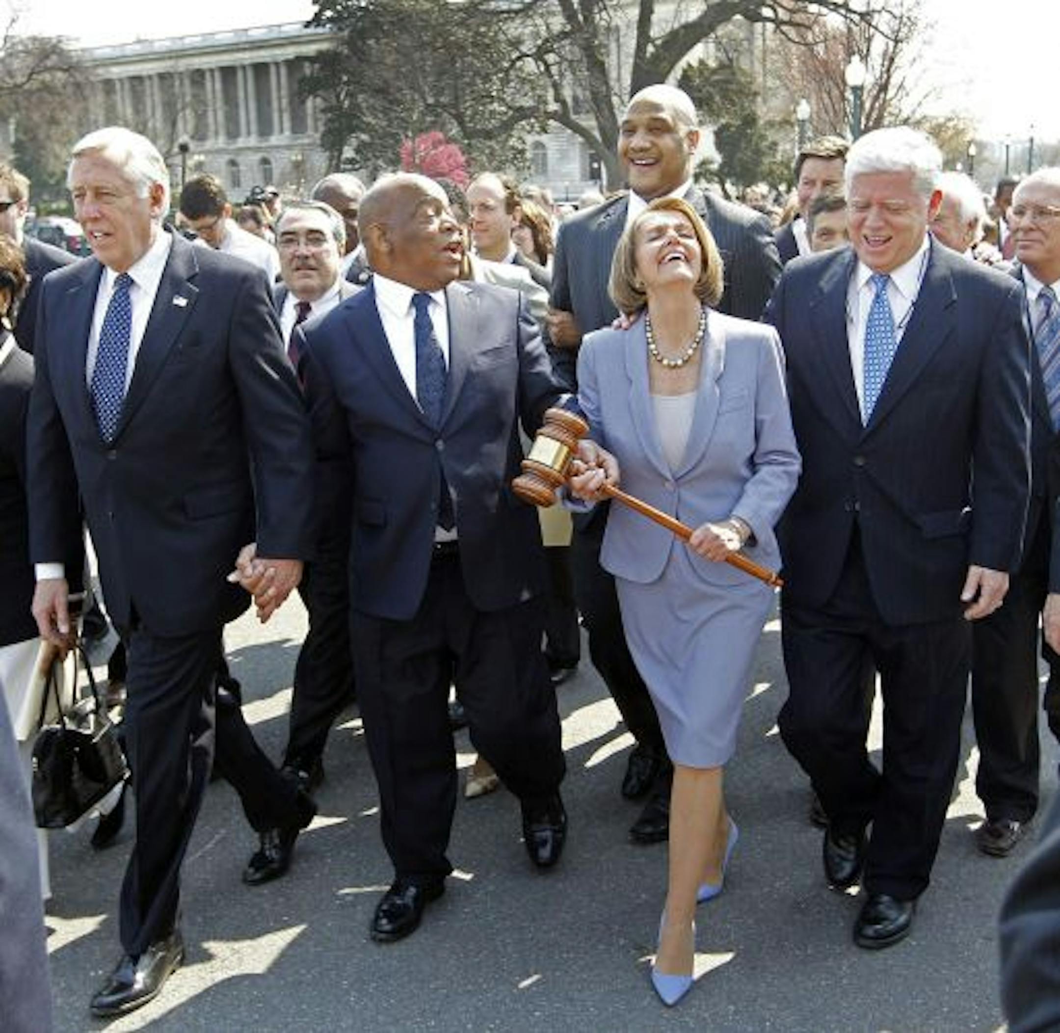 Speaker Nancy Pelosi of California holding the gavel used to pass Medicare Reform, laughs as she walks across the street and into the U.S. Capitol as the House prepares to vote on health care. Walking with her are from left, Rep. Steny Hoyer, D-Md., Rep. John Lewis, D-Ga., and Rep. John Larson, D-Conn.