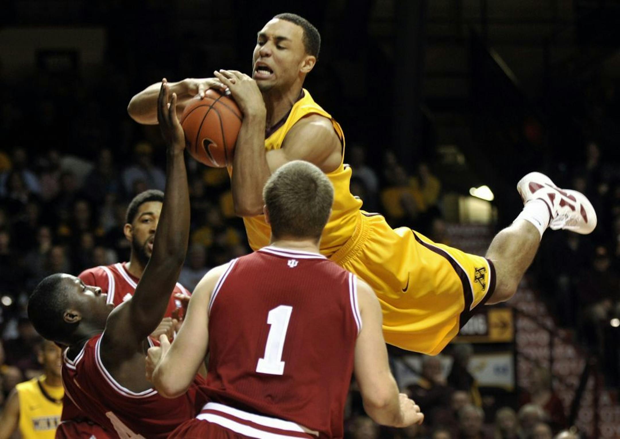 Minnesota's Joe Coleman, top, attempts to maintain control of the ball while sailing into Indiana's Victor Oladipo, left, during the second half of an NCAA college basketball game on Sunday, Feb. 26, 2012, in Minneapolis. Indiana's Jordan Hulls (1) watches the play.