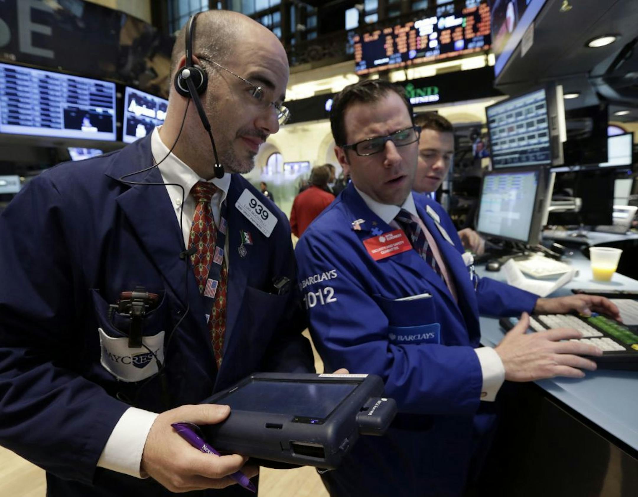 Trader Luigi Muccitelli, left, and specialist Michael Pistillo, center, work on the floor of the New York Stock Exchange Monday, April 29, 2013. A pair of encouraging economic reports helped propel the stock market up in early trading on Monday.