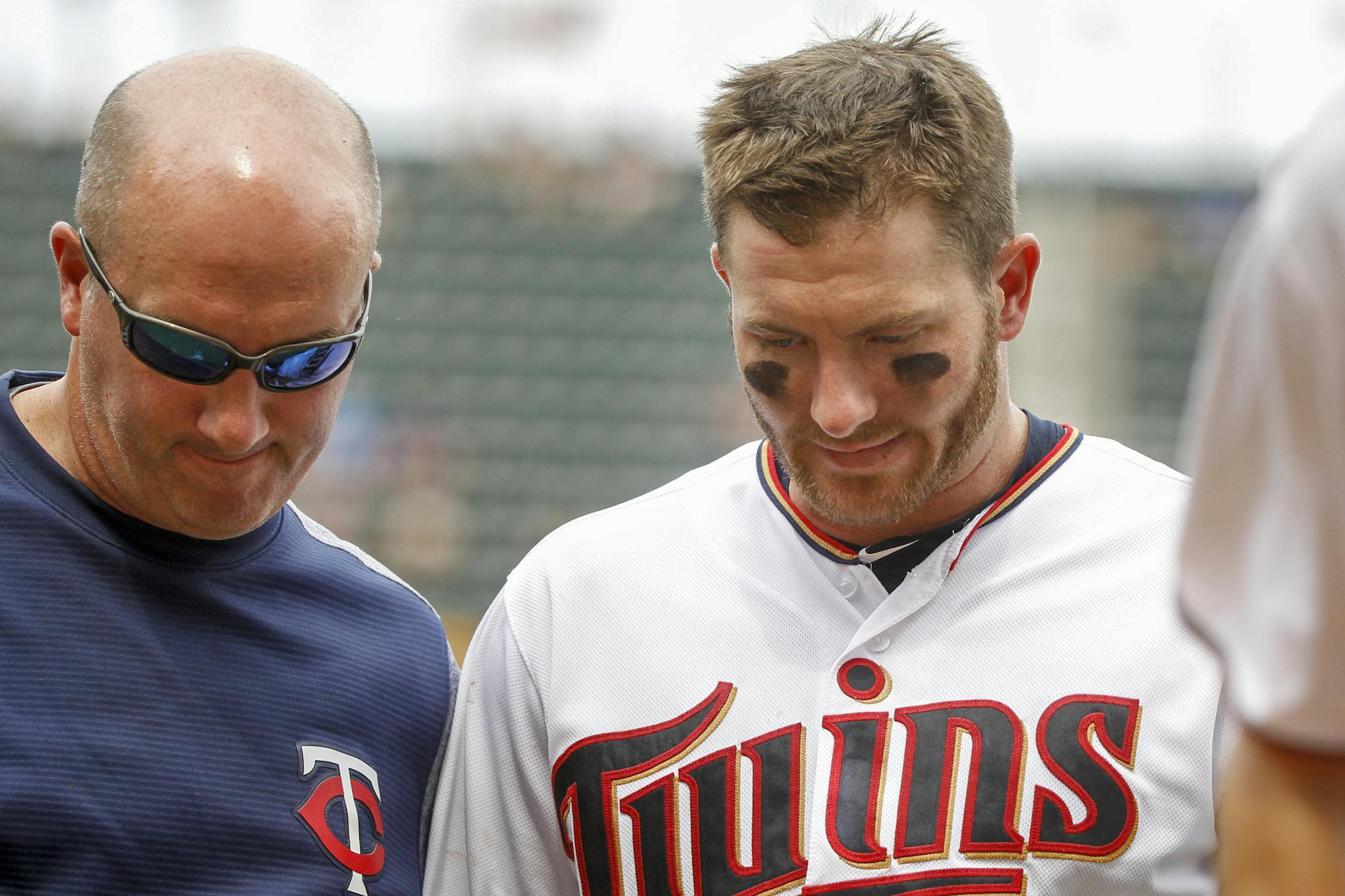 After getting a single against the Kansas City Royals, Minnesota Twins' Robbie Grossman, right, leaves the field with trainer Tony Leo in the seventh inning of a baseball game Sunday, Aug. 5, 2018, in Minneapolis. (AP Photo/Bruce Kluckhohn)