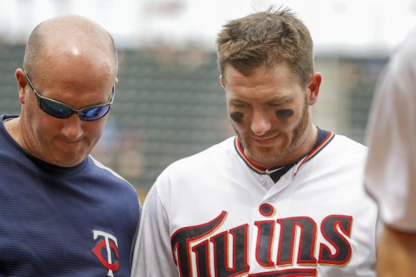 After getting a single against the Kansas City Royals, Minnesota Twins' Robbie Grossman, right, leaves the field with trainer Tony Leo in the seventh 