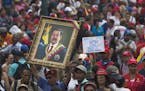 A government supporter holds up a framed image of President Nicolas Maduro during an anti-imperialist rally in Caracas, Venezuela, Saturday, March 30,