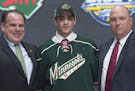 Scout Craig Channell, Luke Kunin and Wild assistant GM Brent Flahr posed after the Wisconsin forward put on a Wild sweater at the NHL draft on Friday 