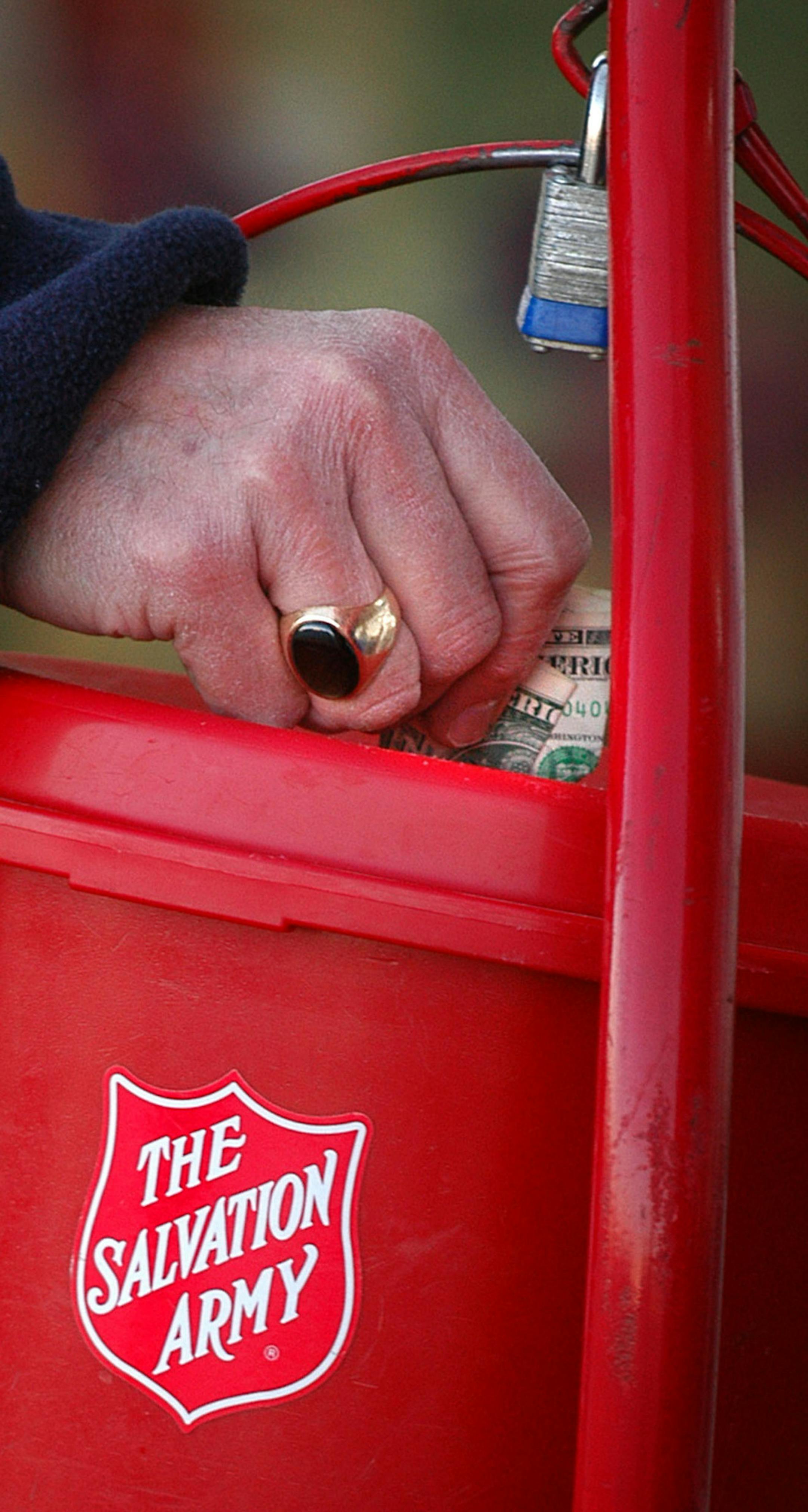 Glen Stubbe/Star Tribune Wednesday, December 1, 2004 -- Apple Valley, Minn. -- A customer puts a donation in David Hill's Salvation Army bucket outside the Cub Foods in Apple Valley Wednesday morning.