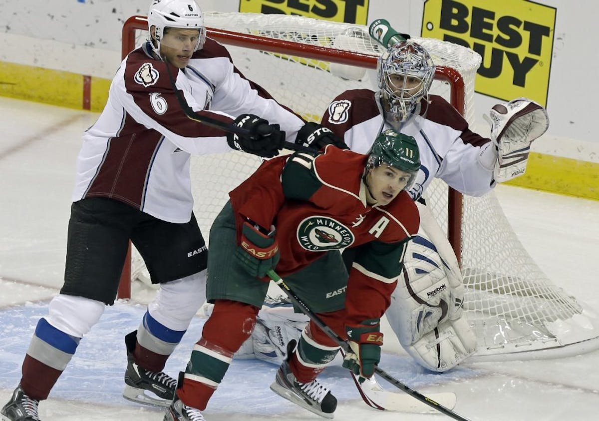 Erik Johnson, left, tries to push the Wild's Zach Parise out of the way of Avalanche goalie Semyon Varlamov