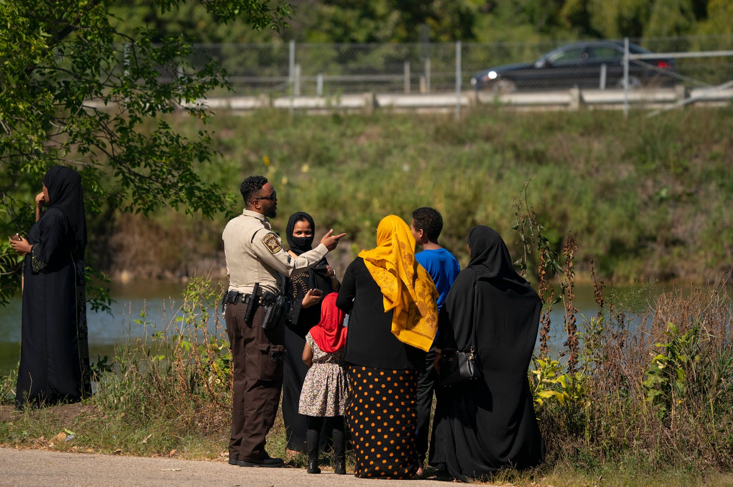 A Hennepin County Sheriff's Deputy stood with community members at the edge of a pond in Rosland Park in Edina where the body of child was recovered Tuesday. ] JEFF WHEELER • jeff.wheeler@startribune.com