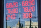 The building of the Russian Foreign Ministry, center back, is reflected in an exchange office sign showing the currency exchange rates in Moscow, Russ