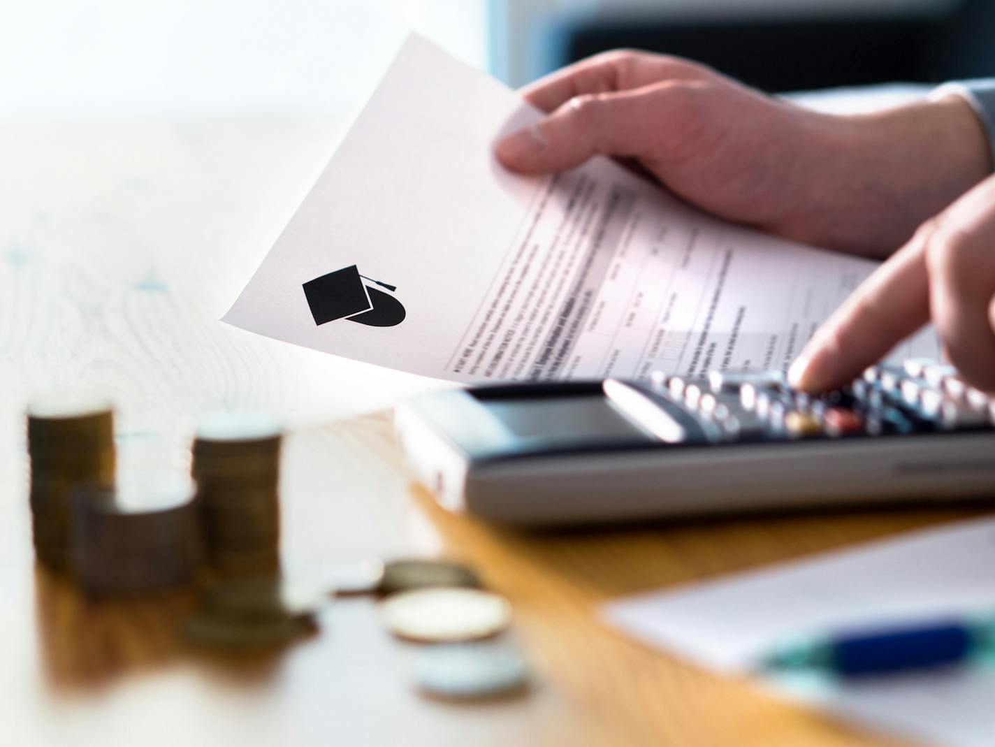 Man counting college savings fund, tuition fee or student loan with calculator. Education price and expenses concept. Money and papers on table. Calculating budget and planning finance.