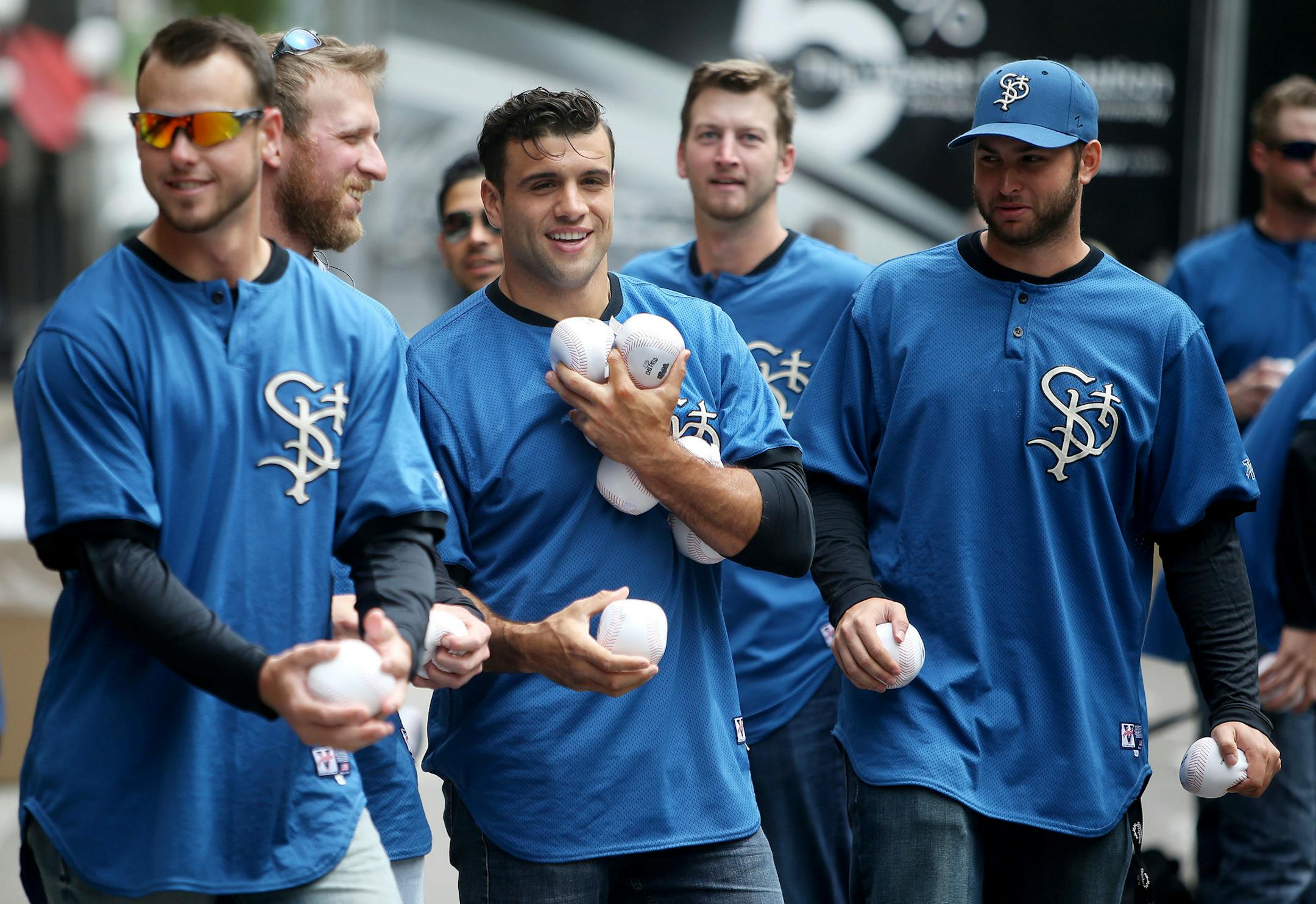 St. Paul Saints catcher Vincent DiFazio, center, is loaded down with soft baseballs that Saints players gave out to passersby before the start of the world's largest game of catch Wednesday, May 20, 2015 in Lowertown, near Mears Park in advance of the St. Paul Saints home opener Thursday.](DAVID JOLES/STARTRIBUNE)djoles@startribune.com world's largest game of catch in Lowertown, near Mears Park in advance of the St. Paul Saints home opener Thursday.**Vincent DiFazio,cq