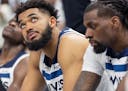 Anthony Edwards, left, Karl Anthony Towns, center, and Naz Reid of the Timberwolves sit on the bench as the clock winds down in the fourth quarter aga