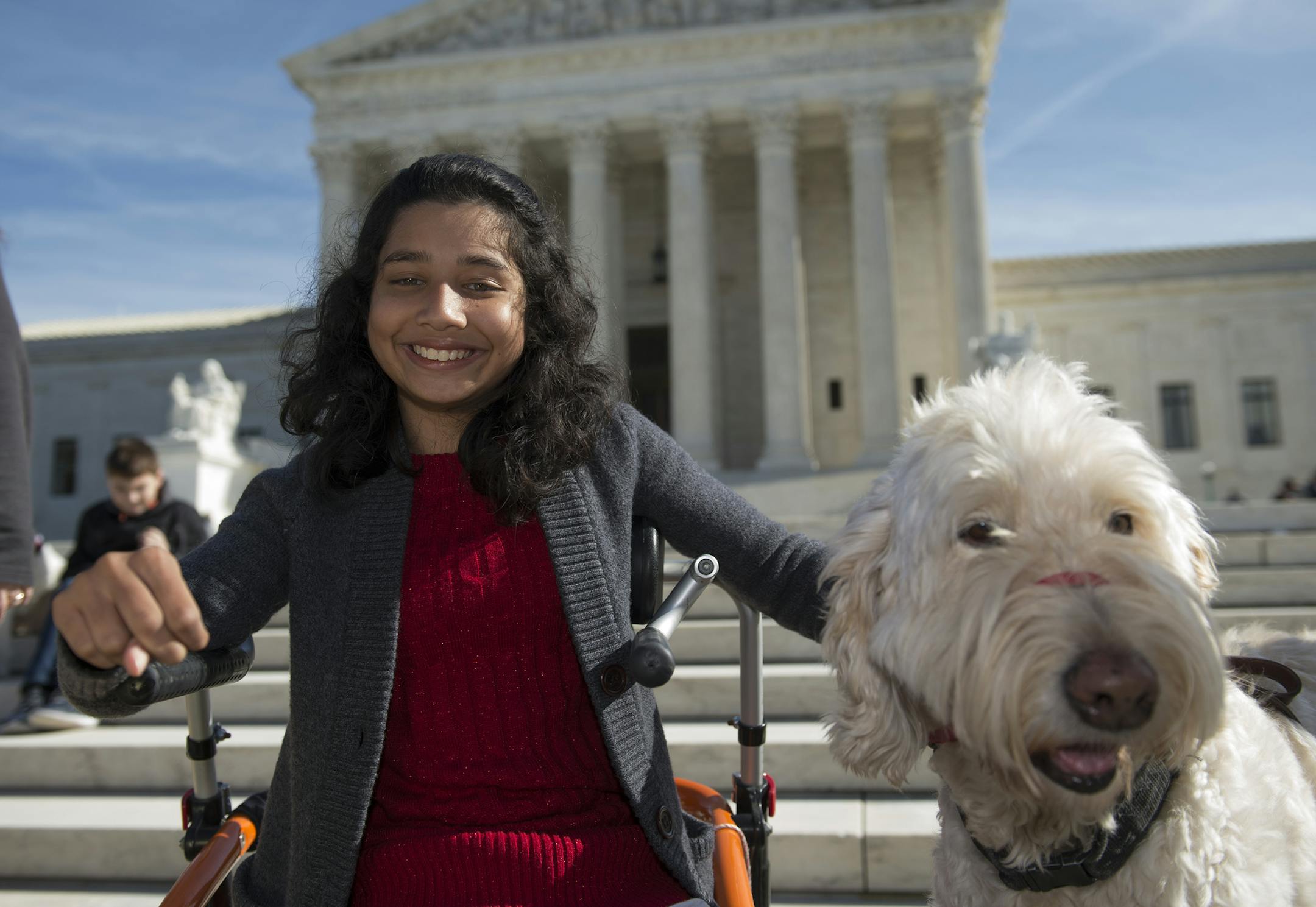 FILE - In this Oct. 31, 2016 file photo, Ehlena Fry of Michigan, sits with her service dog Wonder, while speaking to reporters outside the Supreme Court in Washington. The Supreme Court says a lower court should take another look at whether Fry, who has cerebral palsy can sue Michigan school officials over their refusal to let her to bring a service dog to class. (AP Photo/Molly Riley, File)