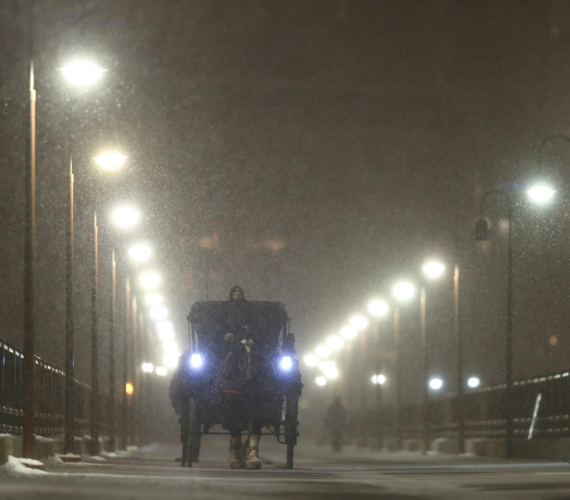 Mike Miller of The Hitching Company carried passengers Noah Perschbacher and Maddie Riegle of Grand Rapids, Michiganin his carriage on an excursion across the Stone Arch Bridge Monday night. ] JEFF WHEELER ï jeff.wheeler@startribune.com Long anticipated snow finally began falling Monday night, December 28, 2015.