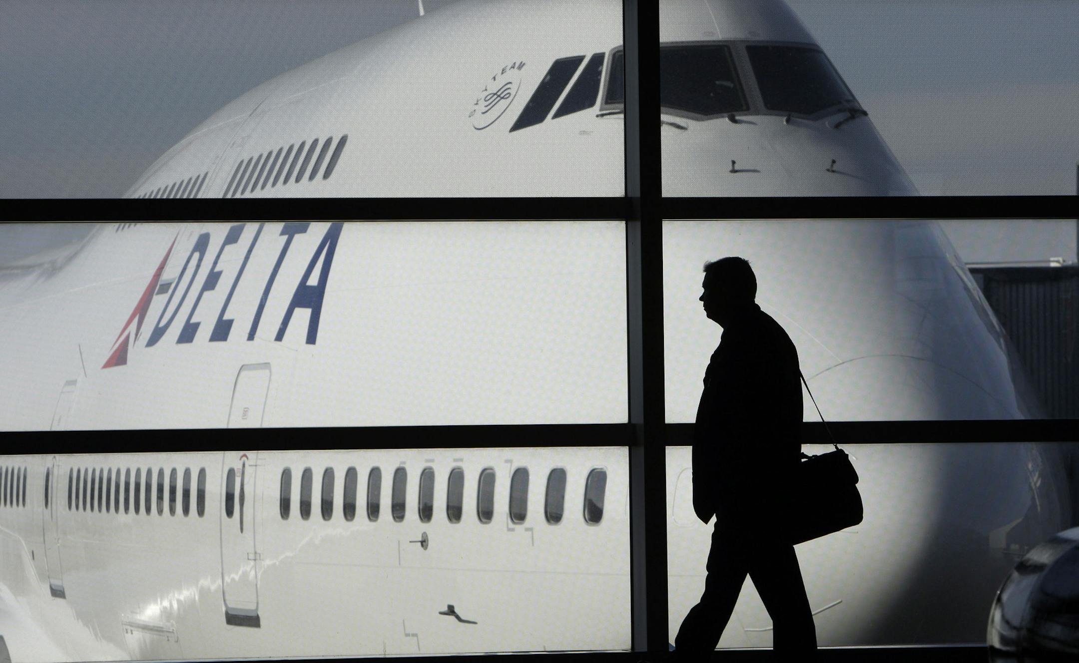 FILE - In this Jan. 21, 2010 file photo, a passenger walks past a Delta Airlines 747 aircraft in McNamara Terminal at Detroit Metropolitan Wayne County Airport in Romulus, Mich. Fares are higher, demand is up and the airlines have established a steady revenue stream from add-on fees for baggage, pillows and food. (AP Photo/Paul Sancya, file) ORG XMIT: MIN2012090615575792
