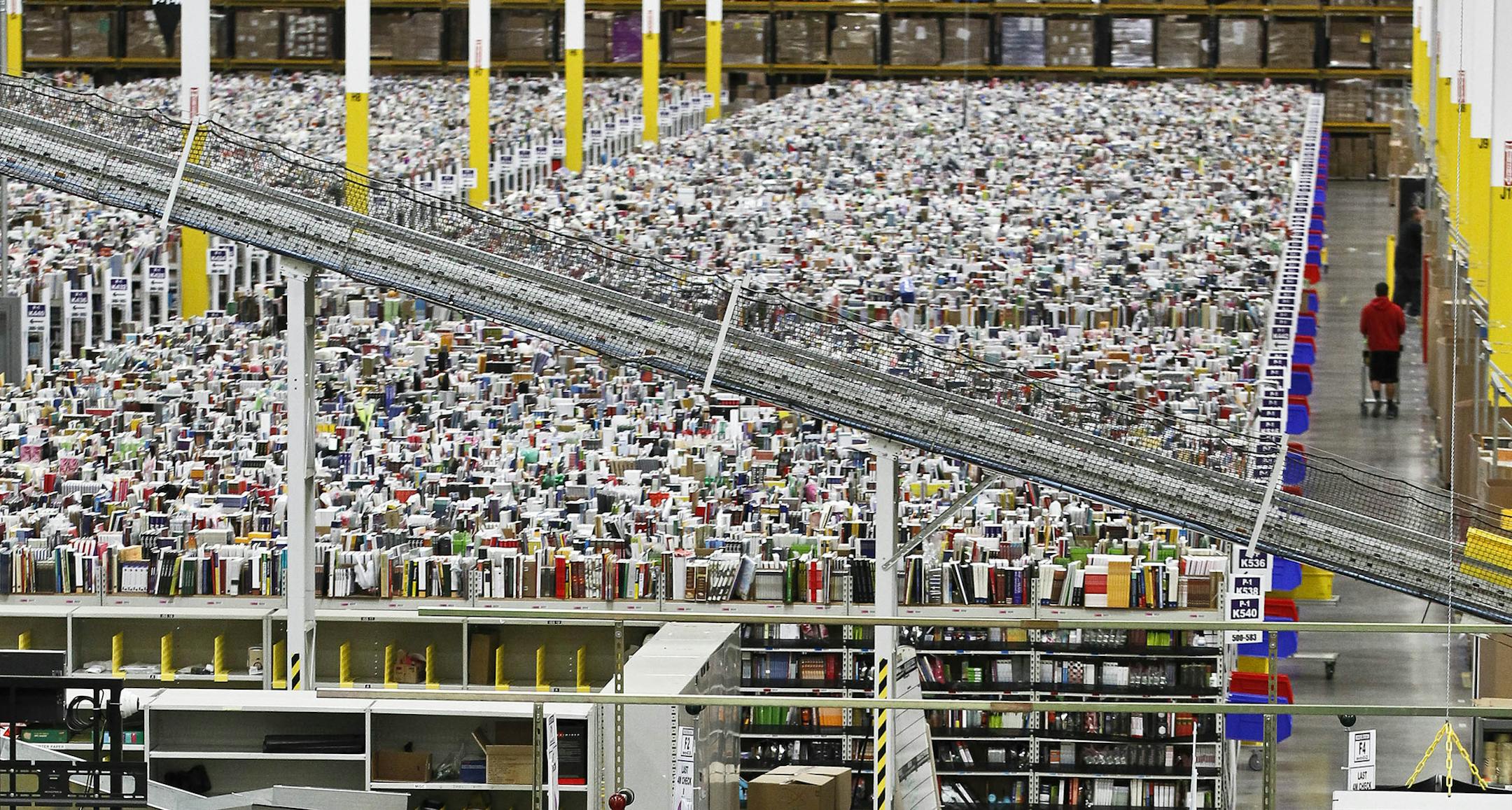 An employee walks a wide isle at Amazon.com's 1.2 million square foot fulfillment center Monday, Nov. 26, 2012, in Phoenix.