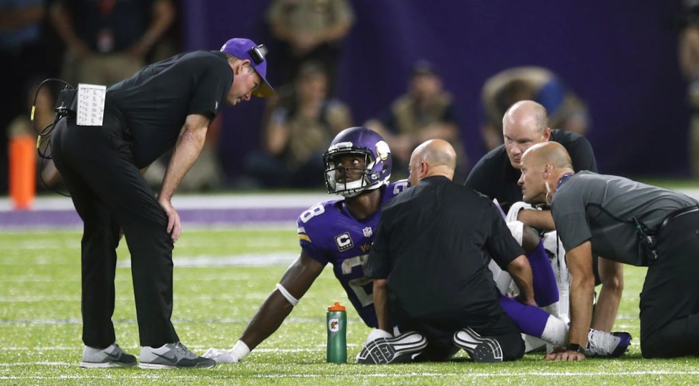 FILE - In this Sept. 18, 2016, file photo, Minnesota Vikings running back Adrian Peterson (28) talks with head coach Mike Zimmer, left, after getting injured during the second half of an NFL football game against the Green Bay Packers, in Minneapolis. Peterson hobbled out of the stadium on crutches. Sam Bradford was shaking his left hand in pain for most of the game. The Vikings took their lumps in a 17-14 win over the Packers on Sunday night, largely due to an offensive line that is struggling