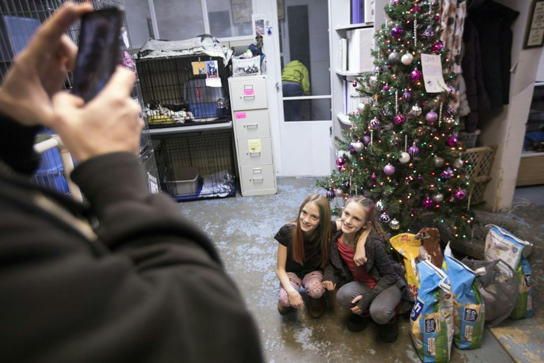 Twin sisters Abby, left, and Isabelle Carlsen pose for a photo taken by their father after they donated items to the Central Dakota Humane Society.
