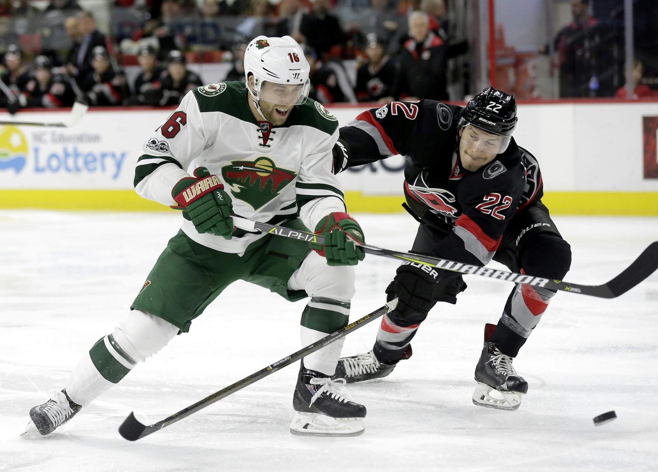 Minnesota Wild's Jason Zucker (16) and Carolina Hurricanes' Brett Pesce (22) chase the puck during the first period of an NHL hockey game in Raleigh, N.C., Thursday, March 16, 2017. (AP Photo/Gerry Broome)
