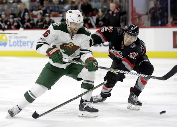 Minnesota Wild's Jason Zucker (16) and Carolina Hurricanes' Brett Pesce (22) chase the puck during the first period of an NHL hockey game in Raleigh, 