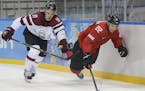 Latvia defenseman Kristaps Sotnieks and Wild forward Nino Niederreiter, who played for Switzerland, chase a loose puck during the third period of a ga