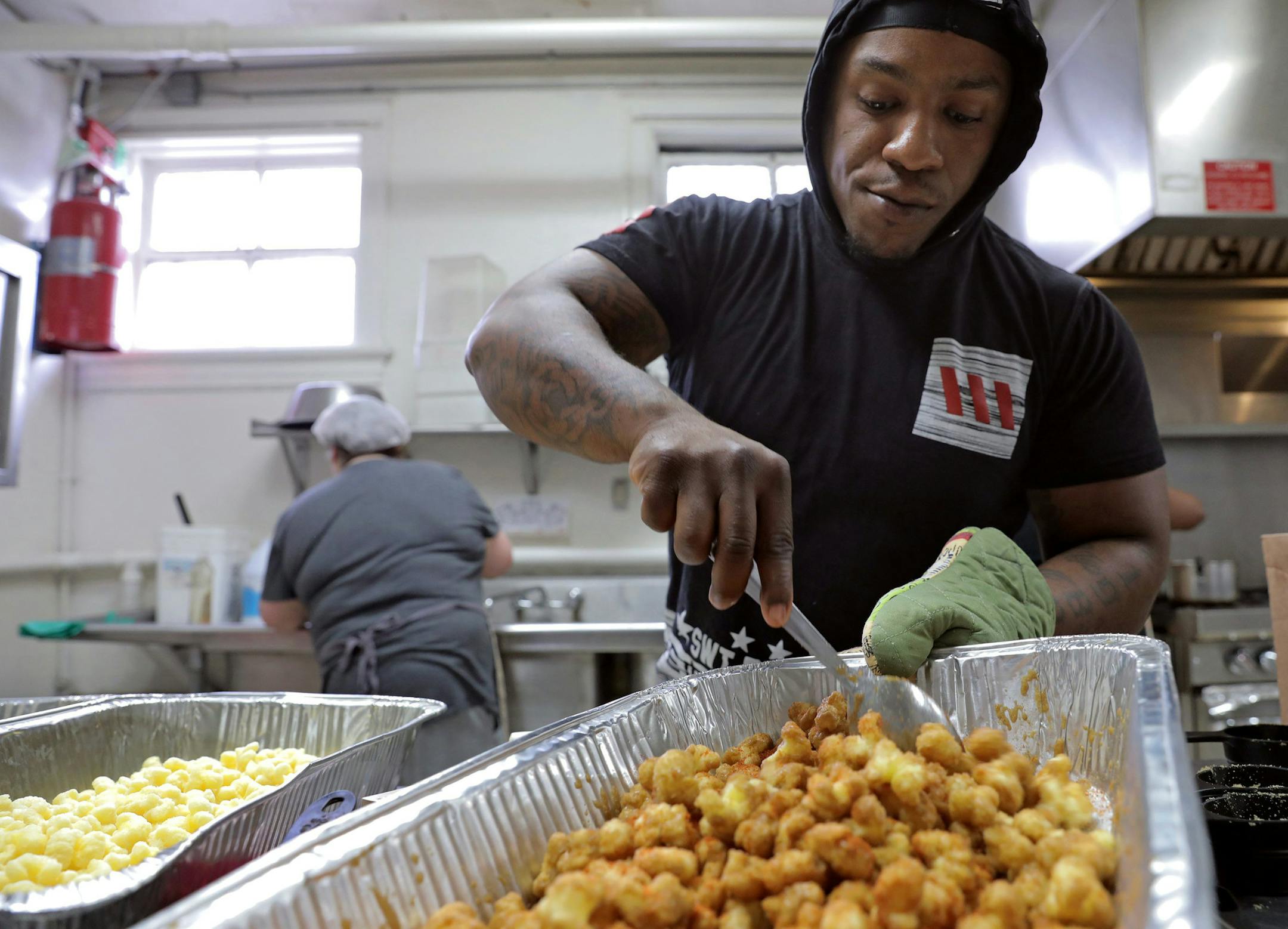 Chip Isadore, 28, of Florissant, makes "bear candy" while Tina Dimtiry (background), 49, of St. Louis, washes dishes at Laughing Bear Bakery on Wednesday, March 25, 2018. The bakery, located in the kitchen of Centenary United Methodist Church in downtown St. Louis, Mo., offers ex-offenders a paid job and a fresh start. (Cristina M. Fletes/St. Louis Post-Dispatch/TNS) ORG XMIT: 1230065